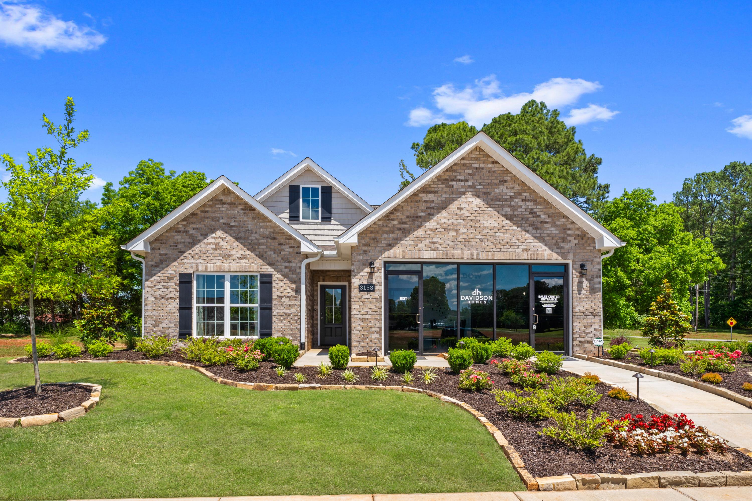 Brick home exterior at Hollon Meadow in Decatur Alabama with covered front porch, large windows, and lush landscaped yard