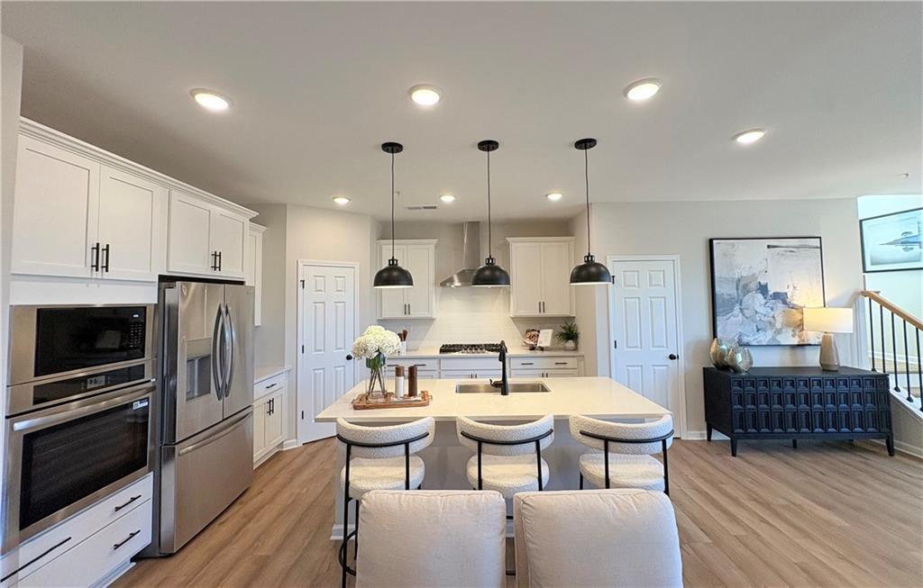 Modern open kitchen with white shaker cabinets, stainless steel appliances, large island, and pendant lights in The Durham D, Cumming, GA