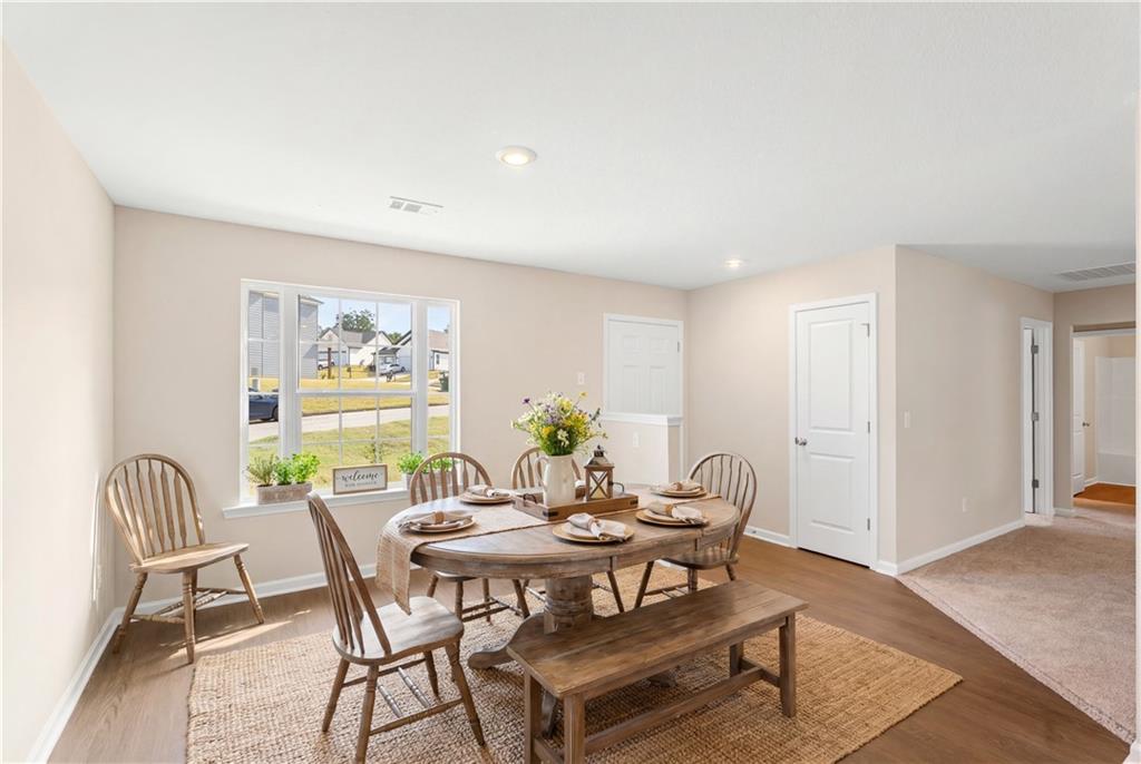Cozy dining room with oval wooden table, benches, and fresh flowers overlooking yard in Davidson Homes The Washington, Phenix City, Alabama