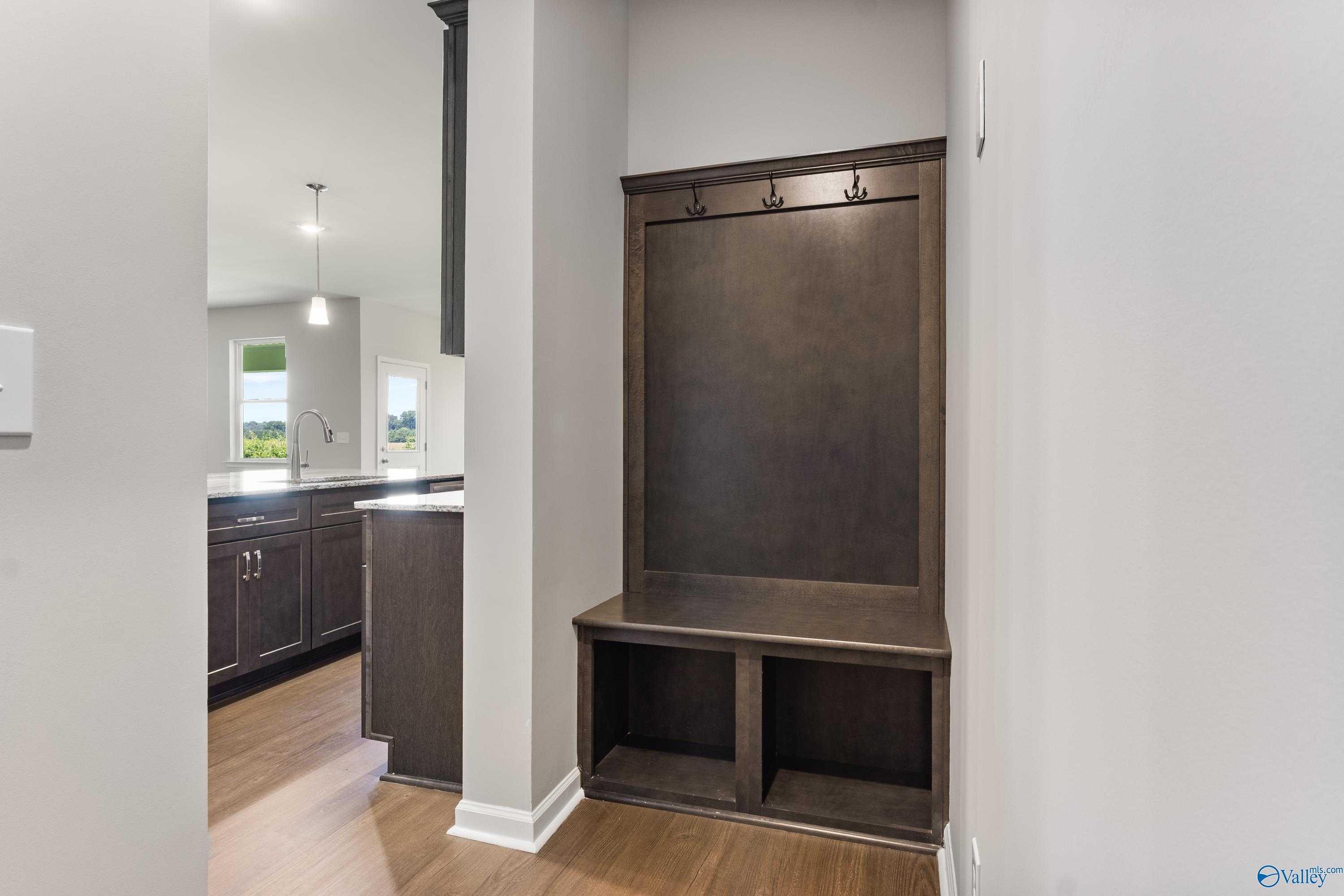 Built-in mudroom bench with coat hooks and storage cubbies near kitchen in Davidson Homes The Sanctuary, Riverton Preserve, Huntsville AL