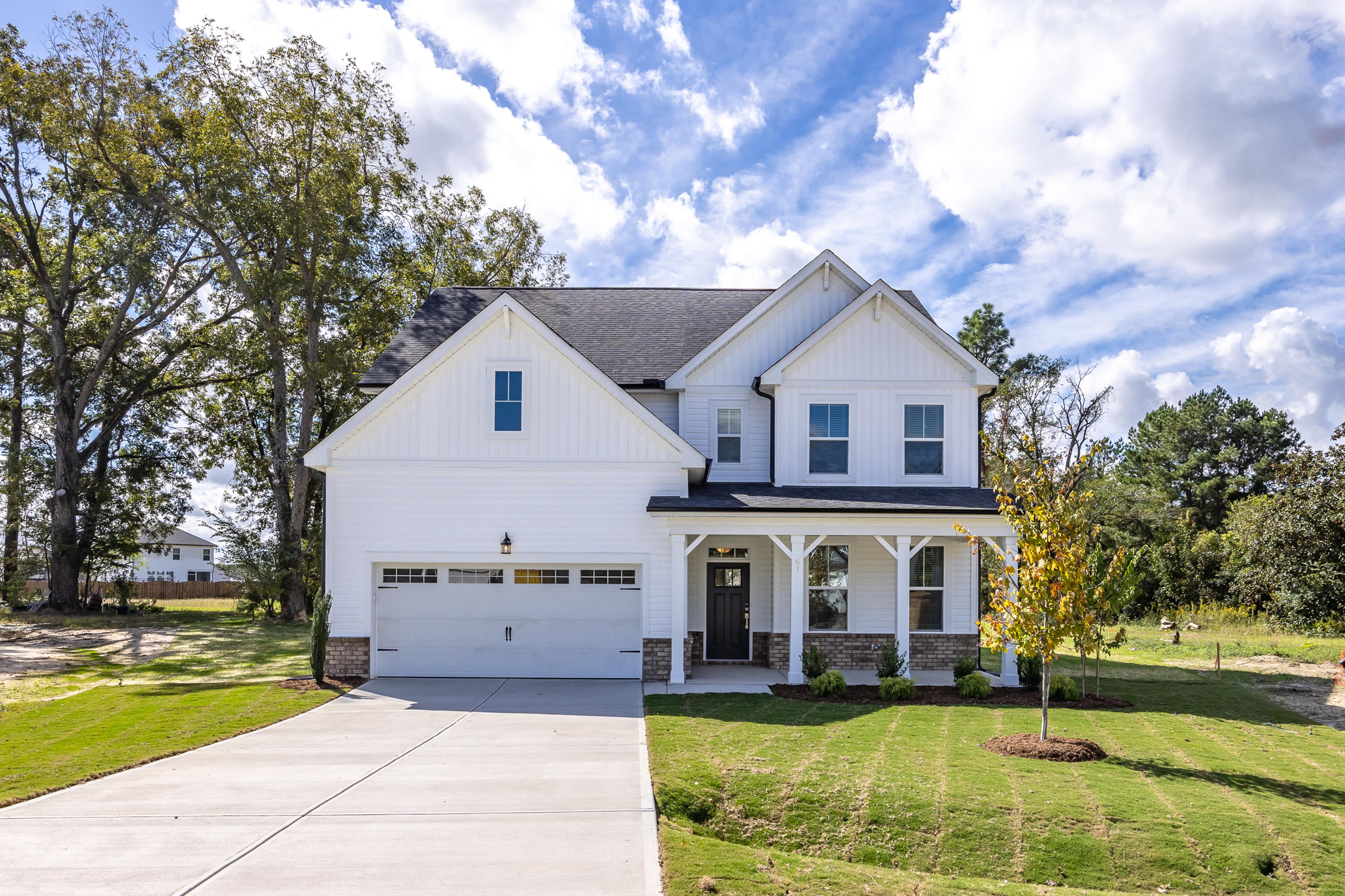 Modern kitchen in Wellers Knoll Lillington NC with white cabinets, stainless steel appliances, island bar, black stools, hardwood floors
