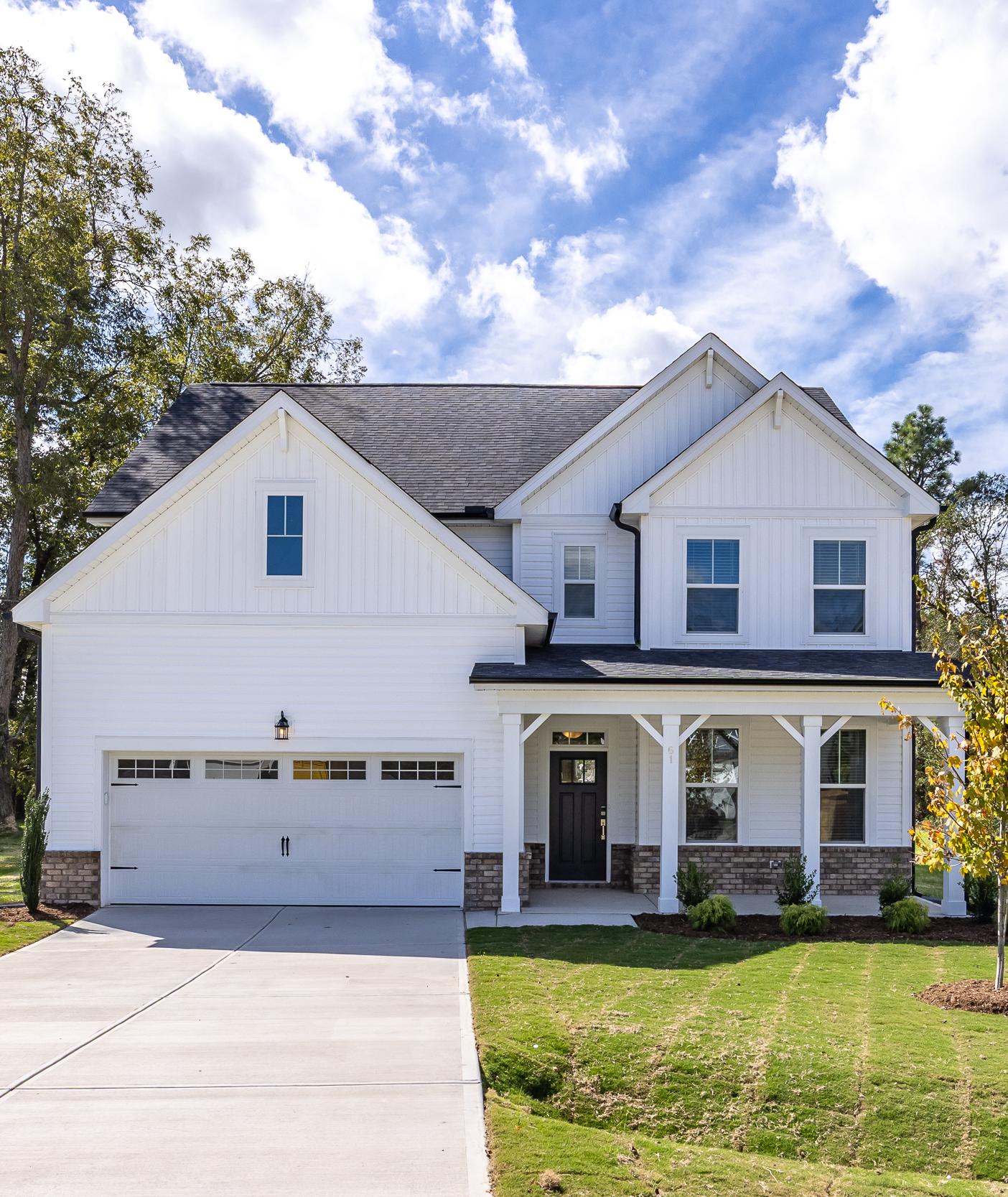 Modern kitchen in Wellers Knoll Lillington NC with white cabinets, stainless steel appliances, island bar, black stools, hardwood floors
