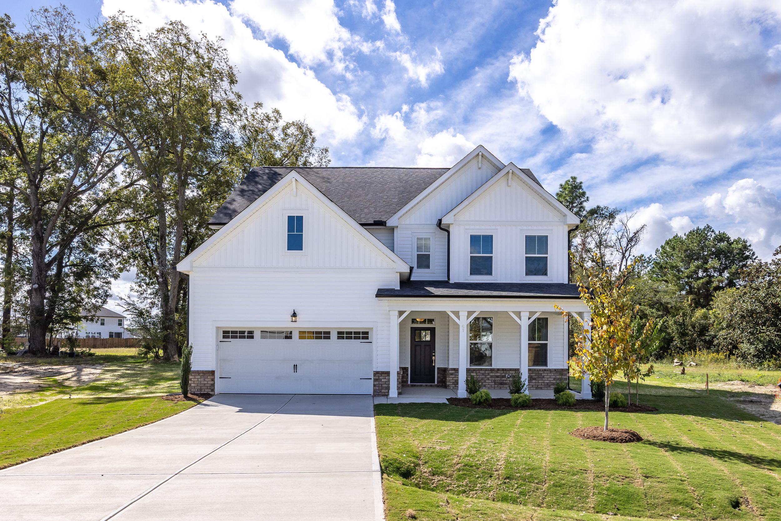 Modern kitchen in Wellers Knoll Lillington NC with white cabinets, stainless steel appliances, island bar, black stools, hardwood floors