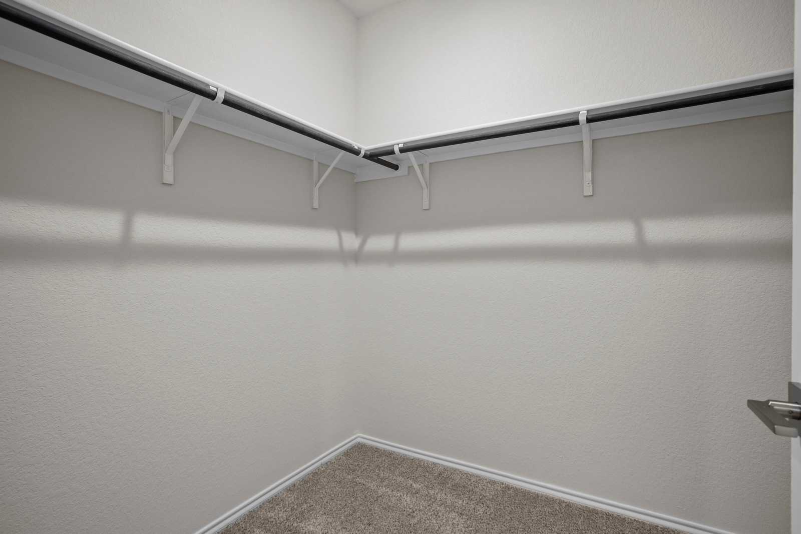 Spacious walk-in closet with white shelving and hanging rods in Davidson Homes The Redbud B, Josephine, Texas