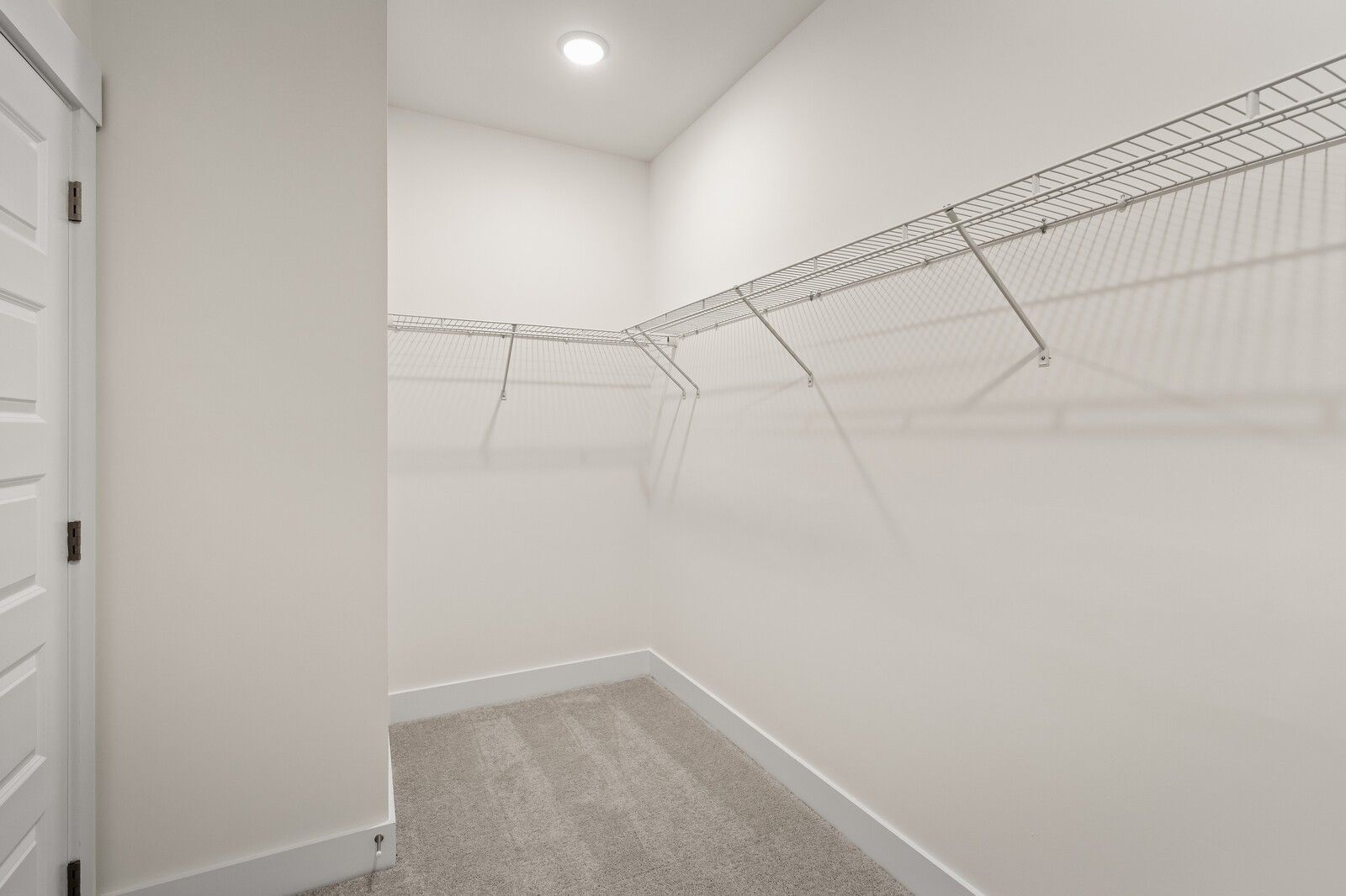 Spacious walk-in closet with wire shelving, white walls, and carpeted floor in Davidson Homes The Ridgeport, Gallatin, TN