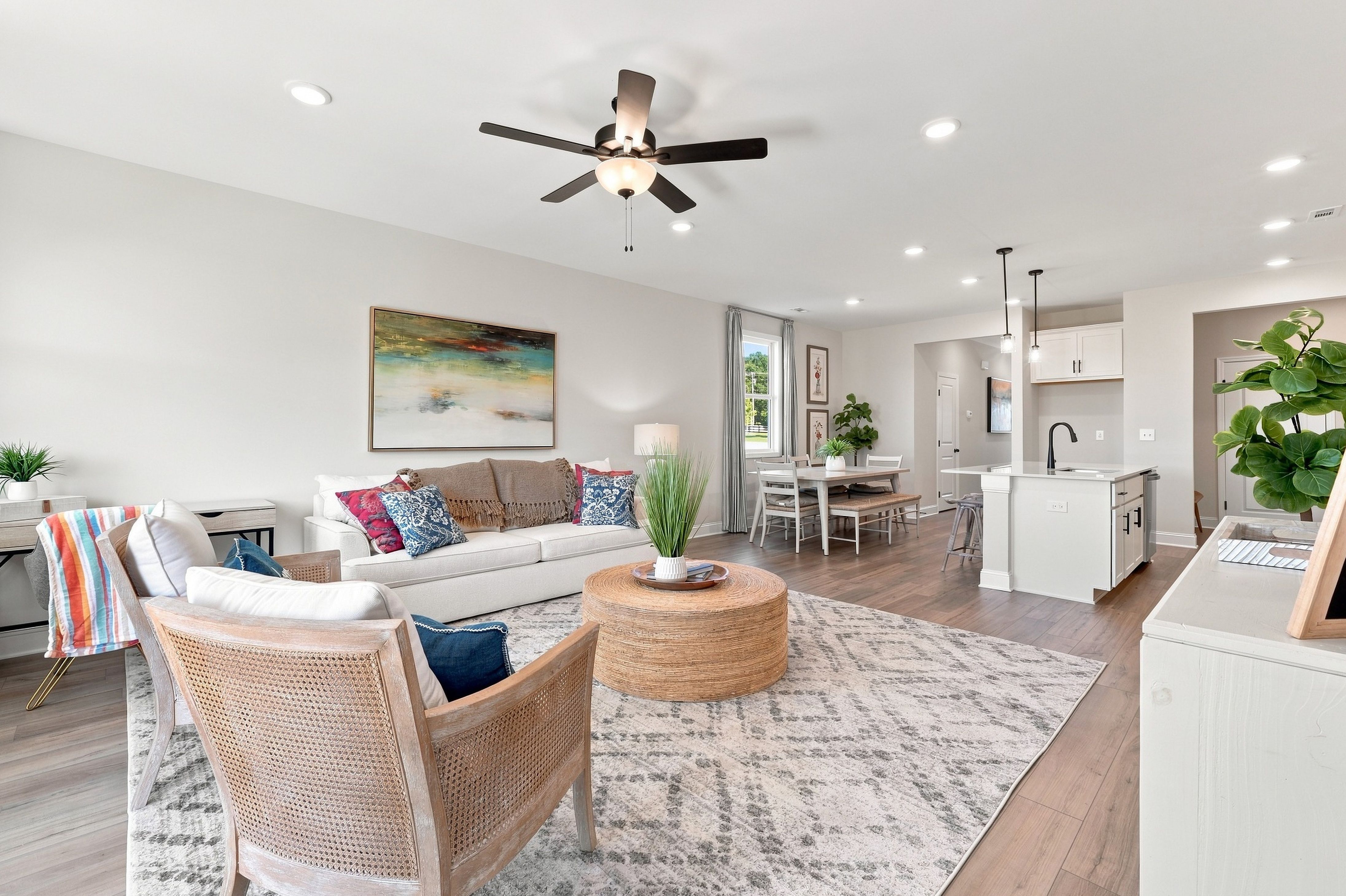Open-concept living room at Bailey Park in Fayetteville, Tennessee with hardwood floors, white kitchen island, and ceiling fan