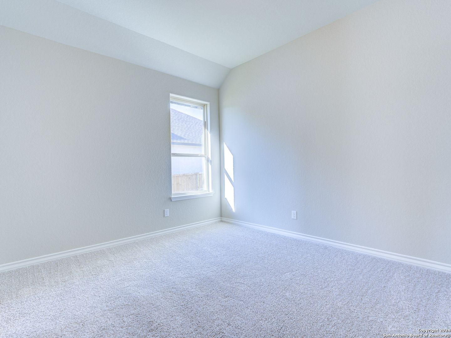 Bright empty bedroom with tray ceiling, beige walls, carpet floor and sunlit window in Davidson Homes The Summerlin A, Castroville, Texas