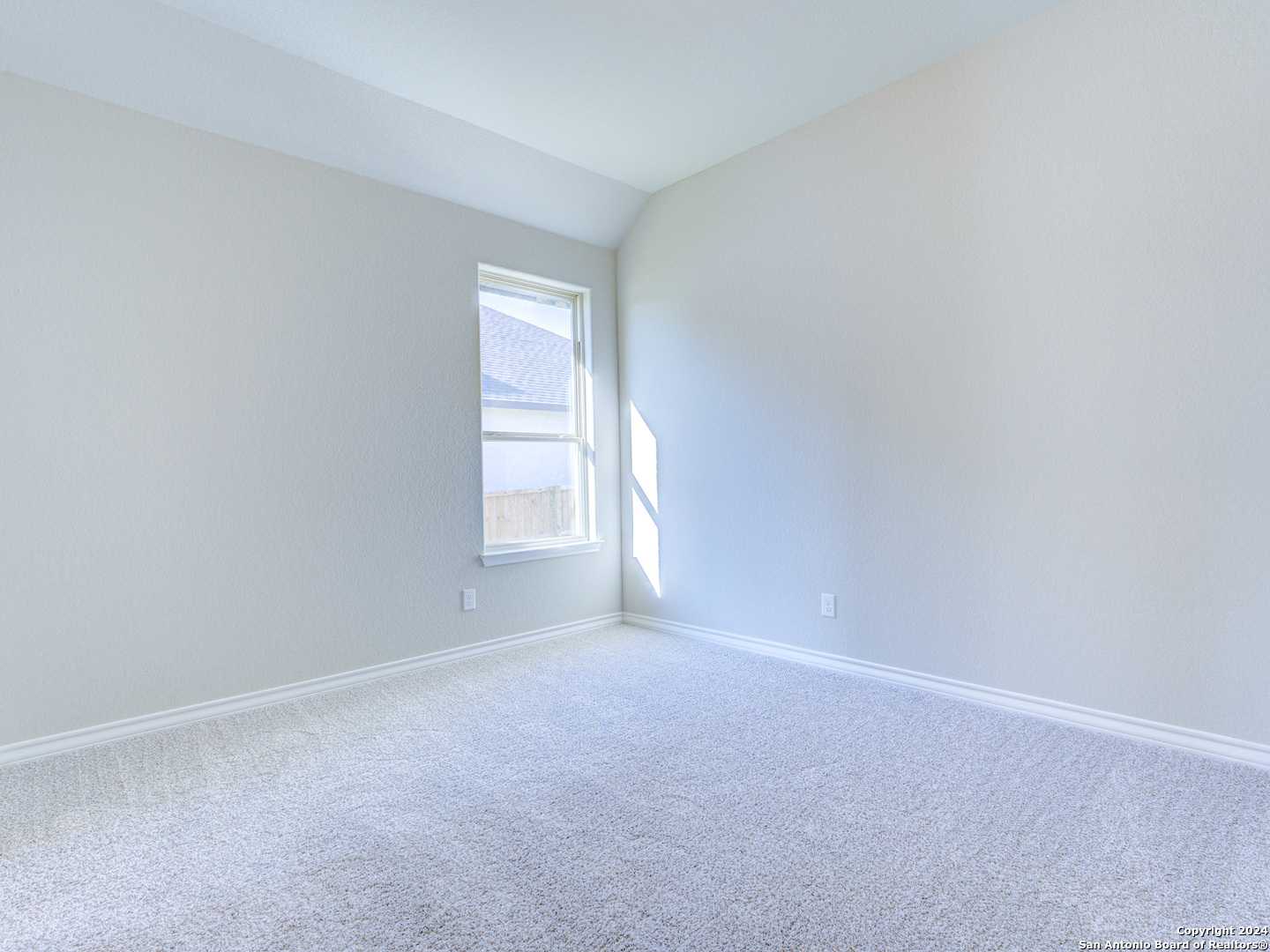 Bright empty bedroom with tray ceiling, beige walls, carpet floor and sunlit window in Davidson Homes The Summerlin A, Castroville, Texas