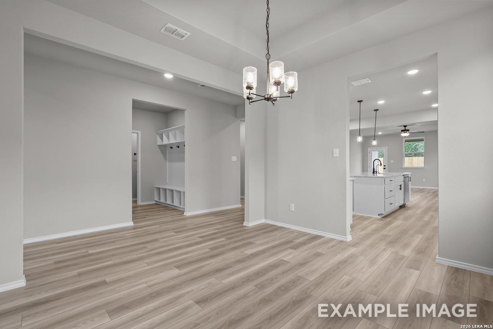 Dining area with chandelier, mudroom, and view into kitchen in The Glenwood E floor plan, Royal Crest, San Antonio.
