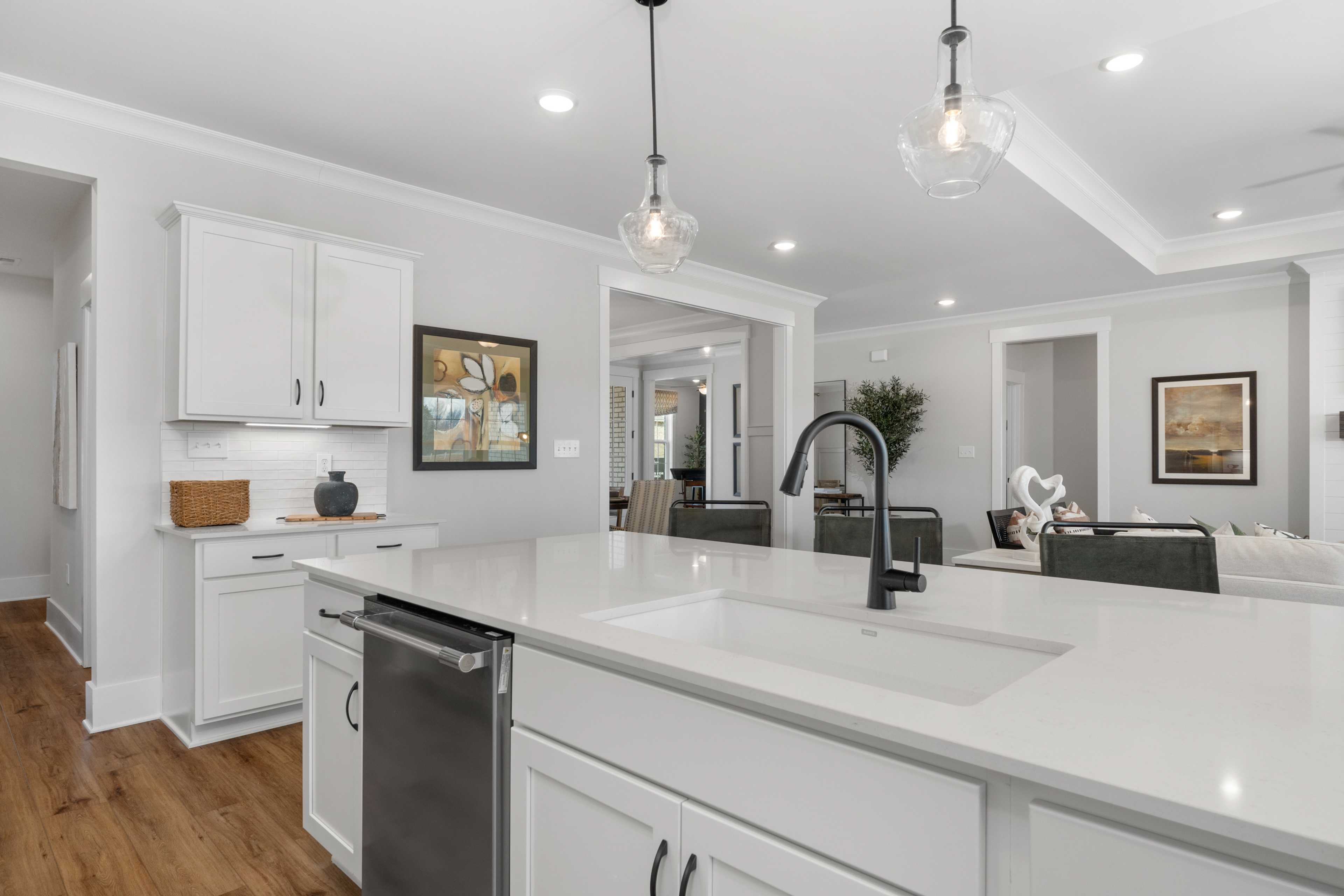Modern kitchen in Briercreek Meridianville AL with white shaker cabinets quartz island black faucet hardwood floors