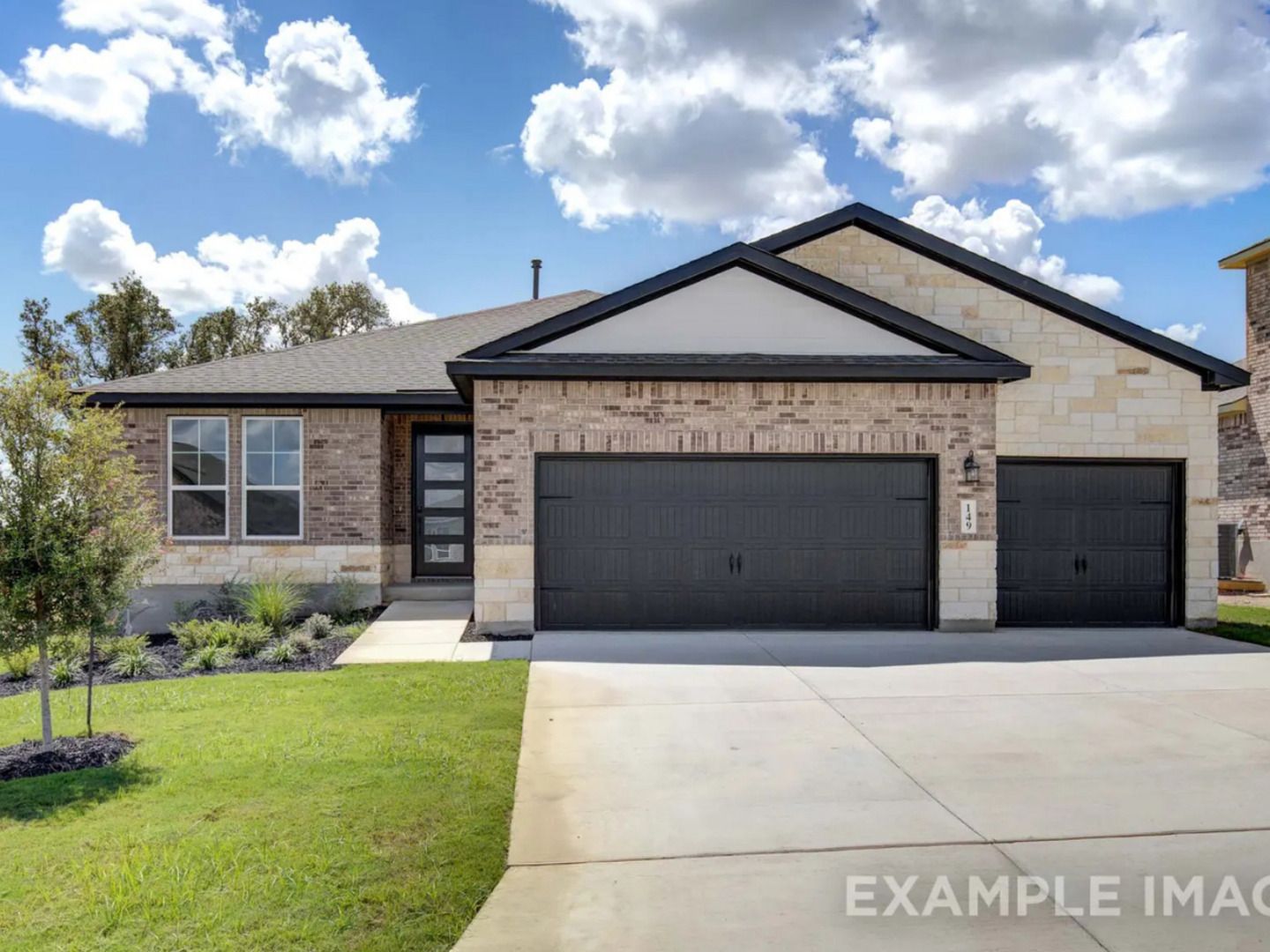 Modern 1-story brick home with stone accents, black 2-car garage, and lush landscaping in The Reserve at Potranco Oaks, Castroville, Texas