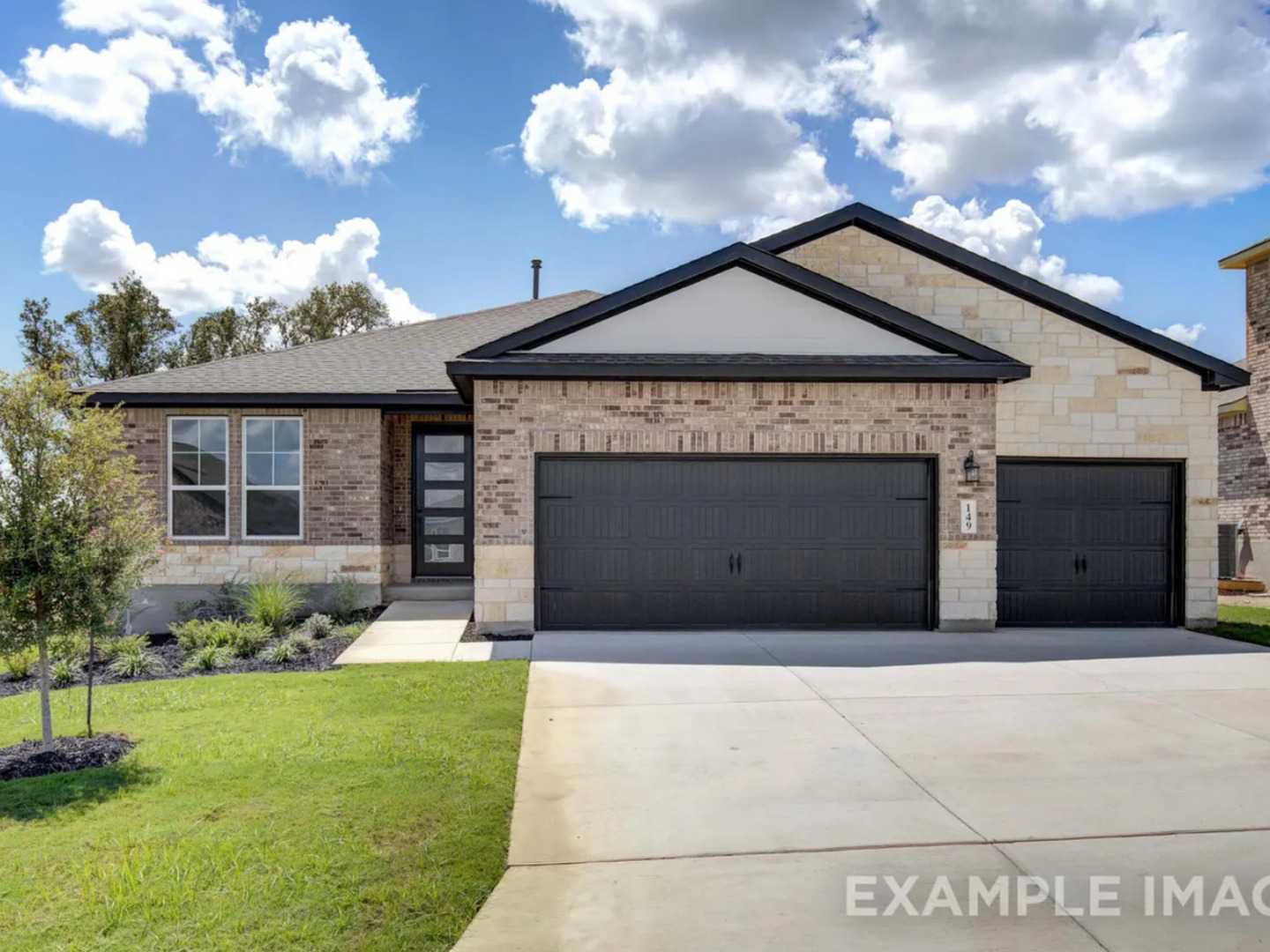 Modern 1-story brick home with stone accents, black 2-car garage, and lush landscaping in The Reserve at Potranco Oaks, Castroville, Texas
