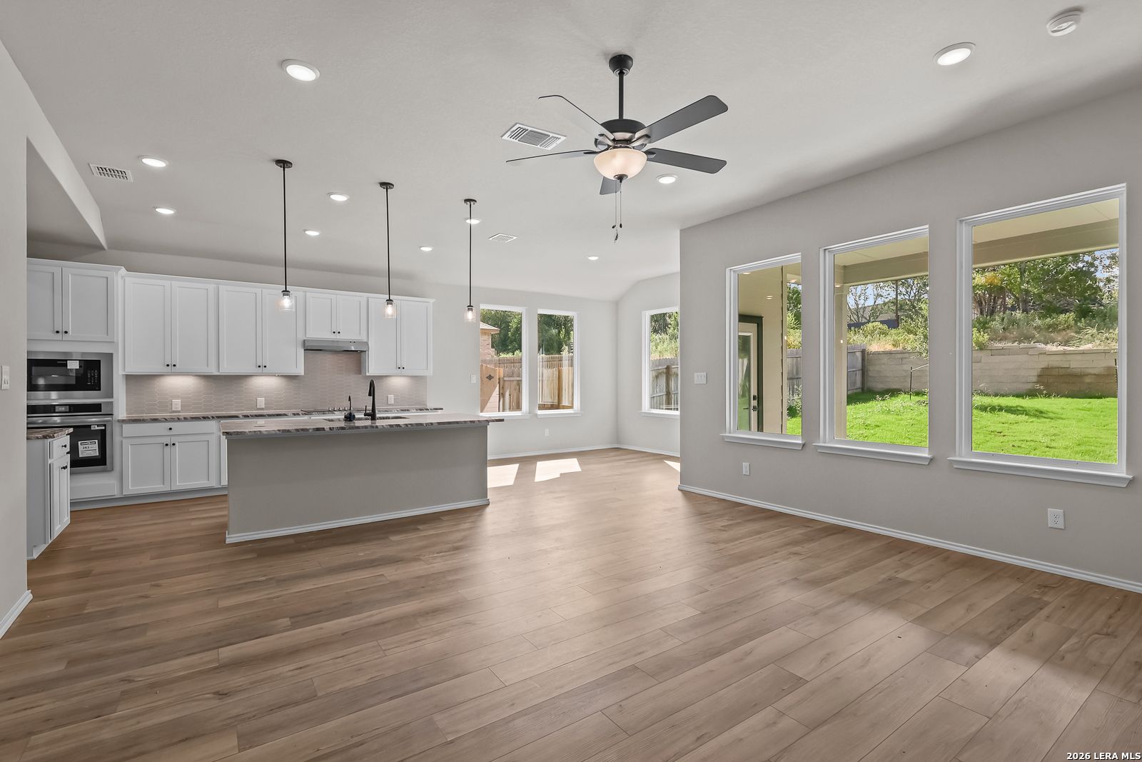 Open-concept kitchen with white cabinetry, island, and hardwood floors in Davidson Homes Sequoia C plan, Royal Crest, San Antonio