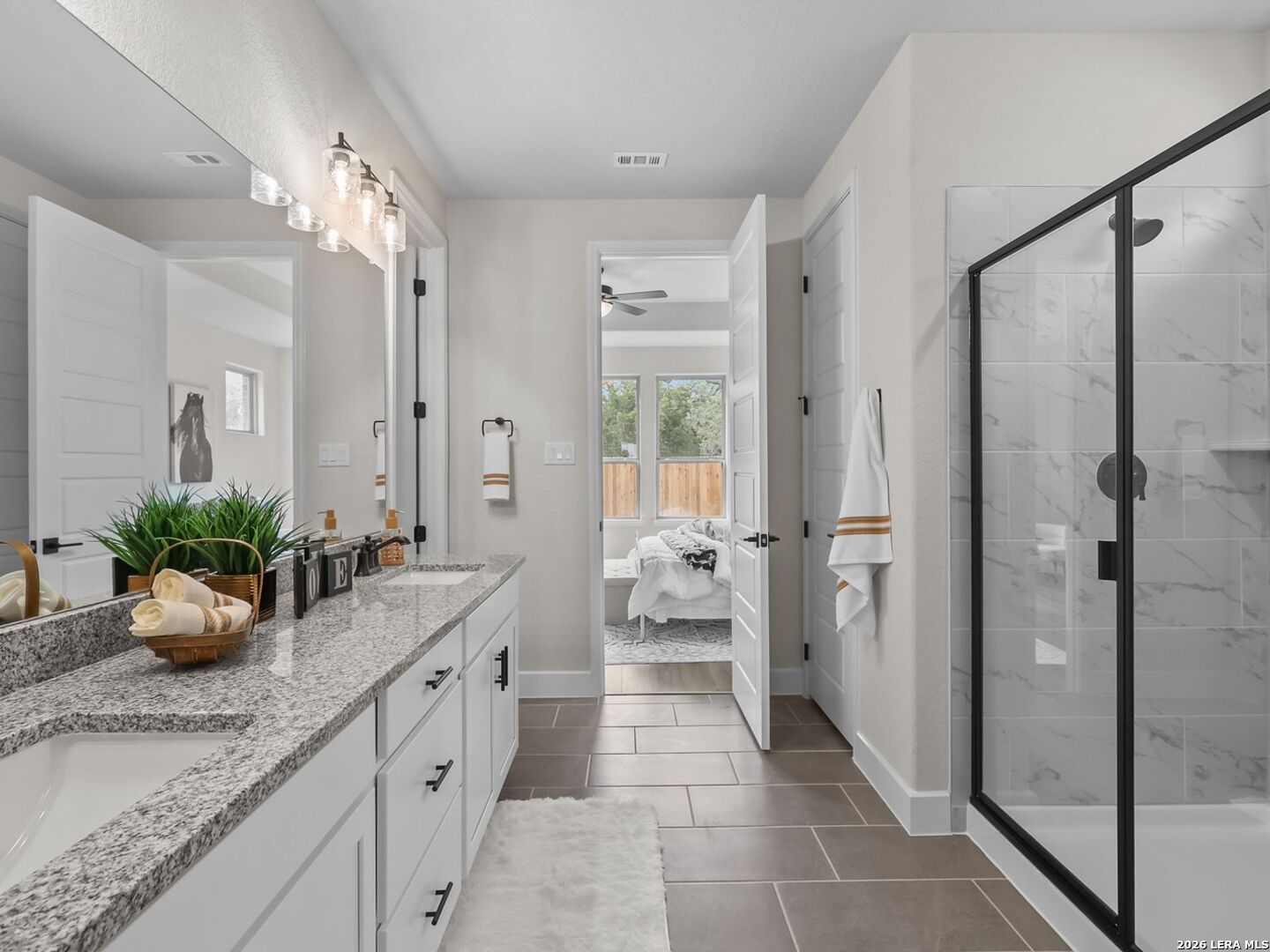 Modern primary bathroom with dual-sink vanity, granite countertops, and glass-enclosed shower in Potranco Oaks home.