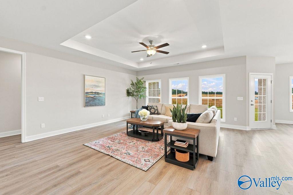 Bright living room with tray ceiling, hardwood-style floors, and large windows in Davidson Homes' The Harrison, Hartselle, Alabama