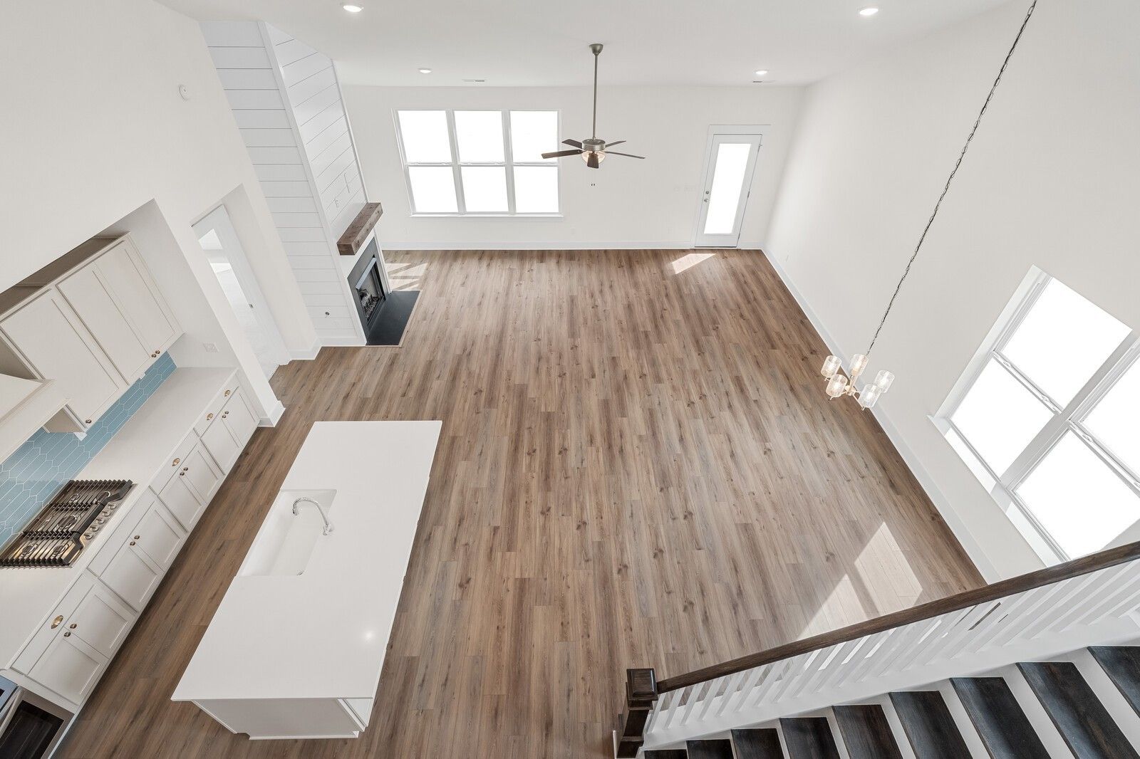 Open-concept kitchen and great room with wood floors, white island, fireplace, and large windows in Davidson Homes The Ridgeport, Gallatin TN