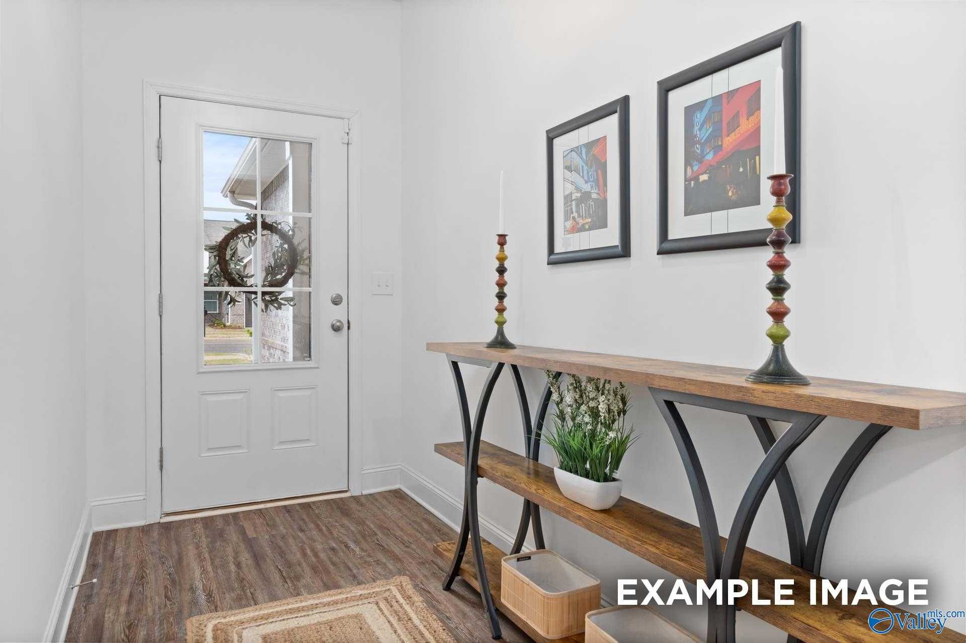 Welcoming entryway with front door wreath, wooden console table, artwork, and potted plant in Davidson Homes The Cumberland, Decatur AL