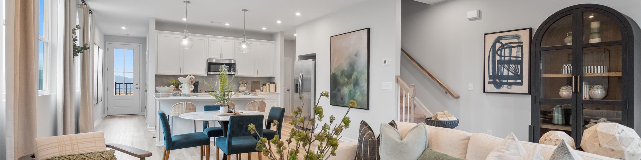Open-concept living room at Retreat at North Main in Lillington NC with gray sectional sofa, hardwood floors, arched mirror, and modern kitchen