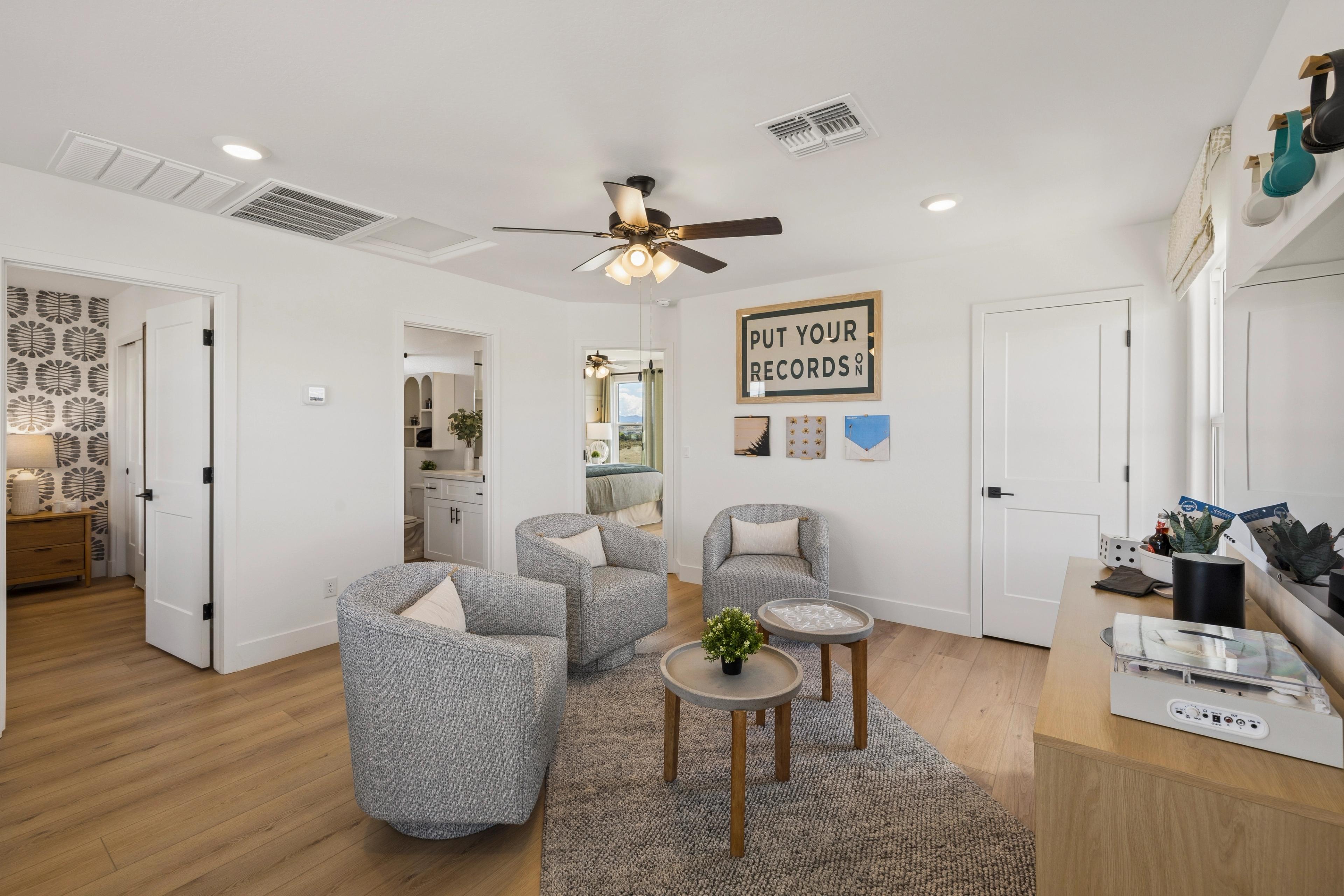 Cozy modern nook with gray swivel chairs, record player, plants, and wall art in South Ranch Southern Collection home, Prescott AZ