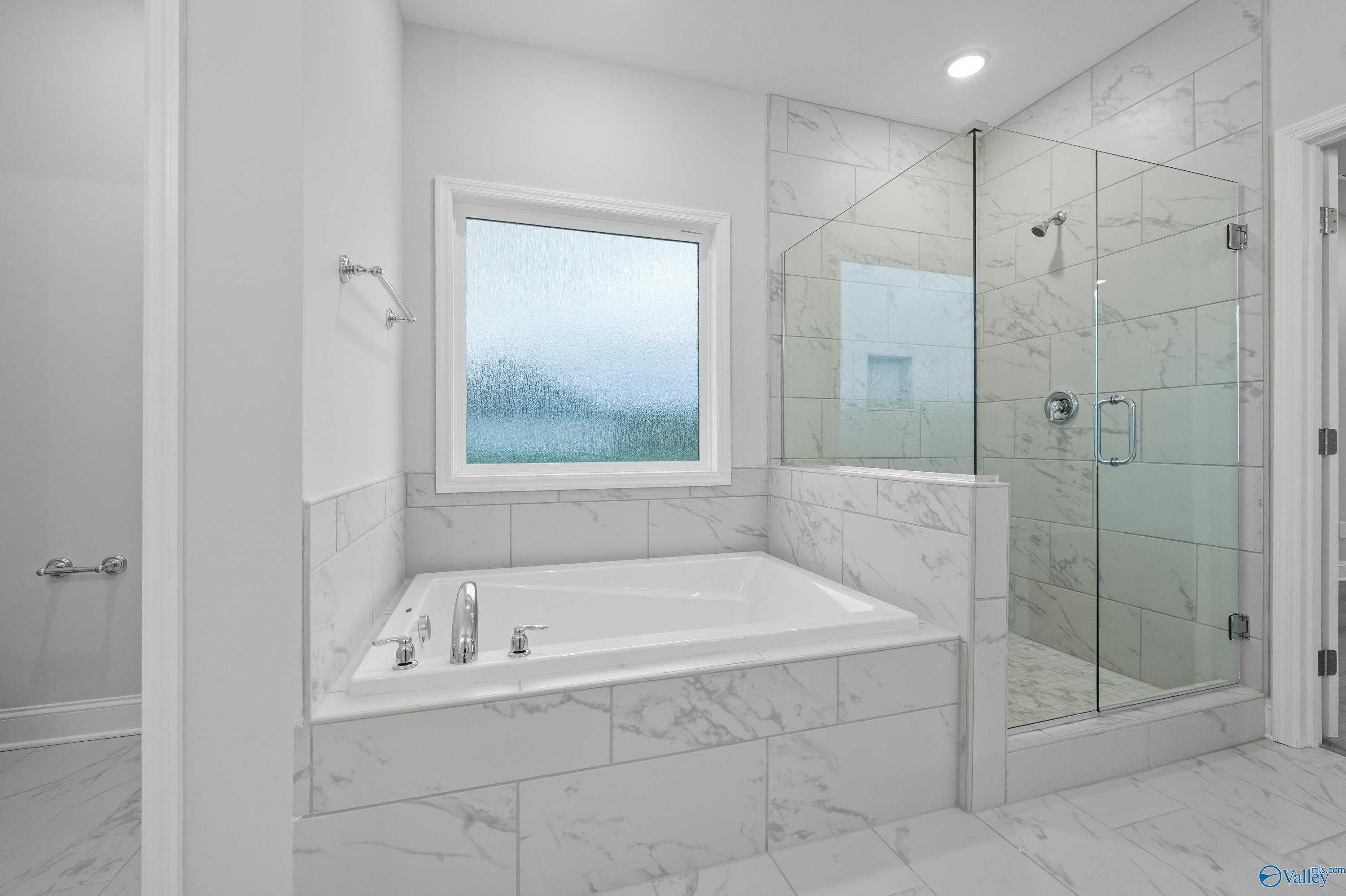 Elegant master bathroom with soaking tub, frameless glass shower, and subway tile in Davidson Homes The Lanier, Harvest, Alabama
