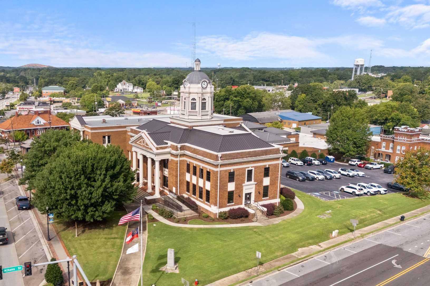 Aerial view of historic red brick courthouse in Winder Georgia with clock tower, American flag, and tree-lined streets
