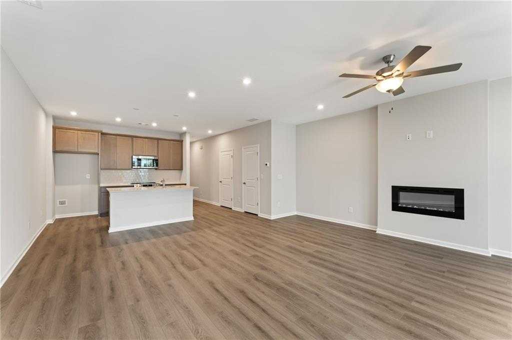Spacious open-concept living room with gas fireplace, ceiling fans, and hardwood floors in Davidson Homes The Monroe A, Emerson, Georgia