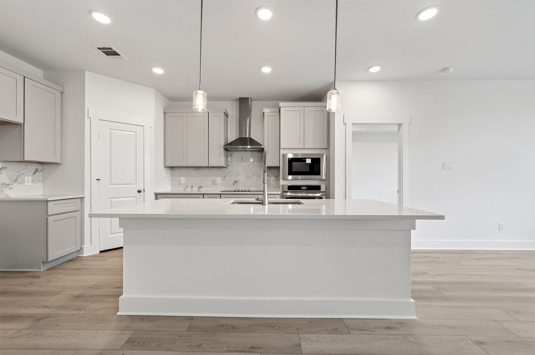 Bright open-concept kitchen with large island, pendant lights, and stainless appliances in The Holly F plan, Josephine, Texas