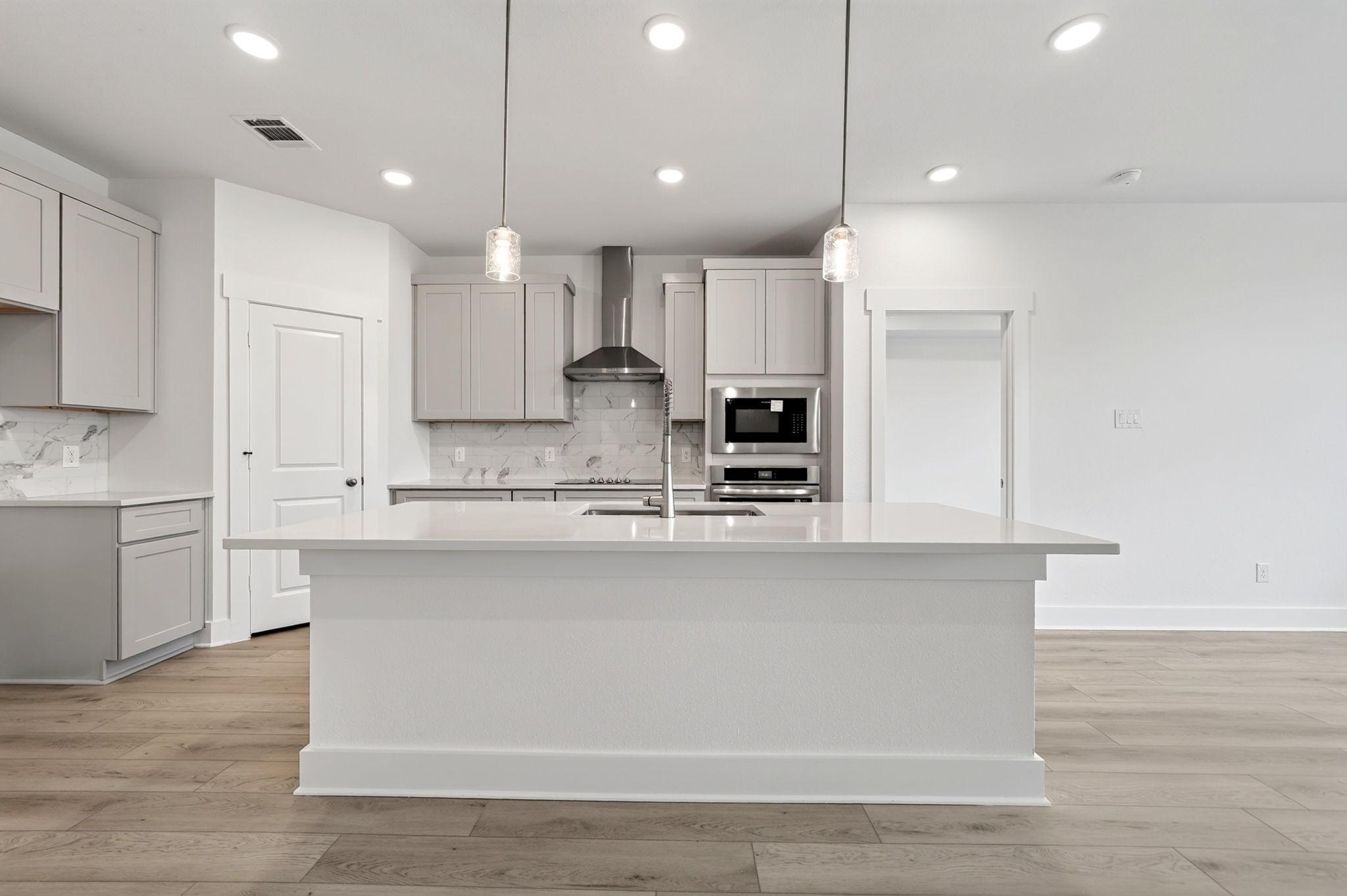 Bright open-concept kitchen with large island, pendant lights, and stainless appliances in The Holly F plan, Josephine, Texas