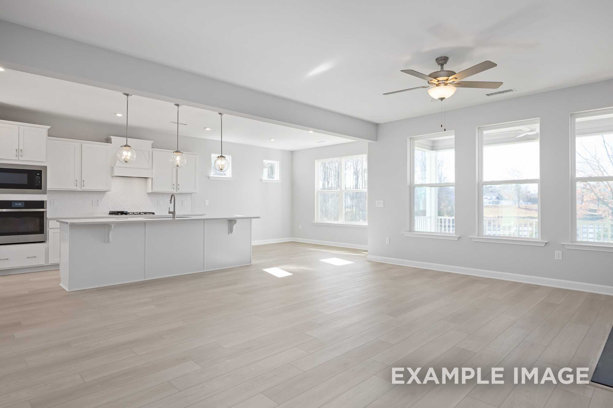 Spacious open-concept kitchen in The Cypress D II with white cabinets, large island, double oven, and natural light from windows