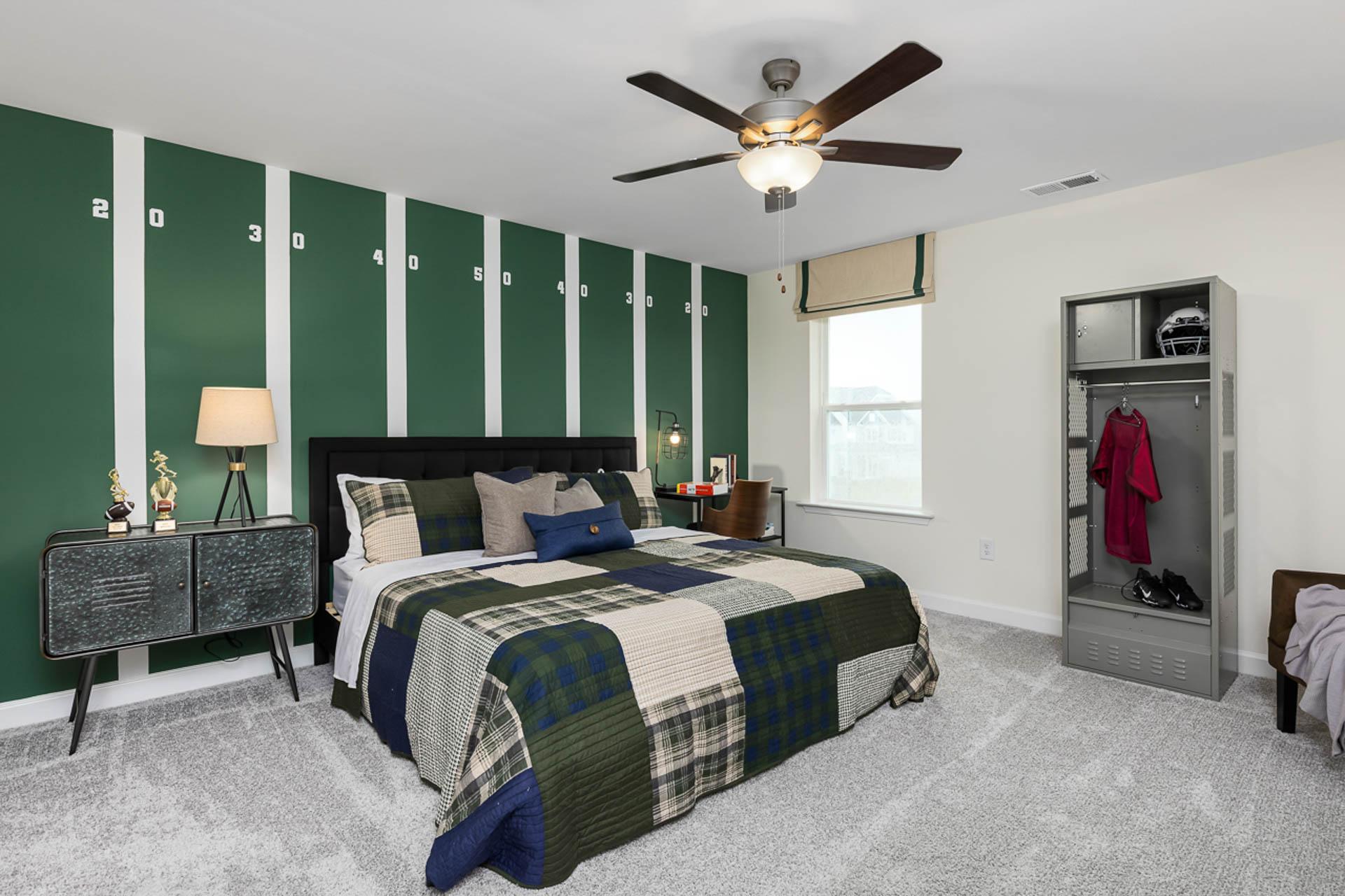 Football-themed bedroom at Weatherford East in Angier NC with green striped walls, plaid bedding, ceiling fan, and sports locker