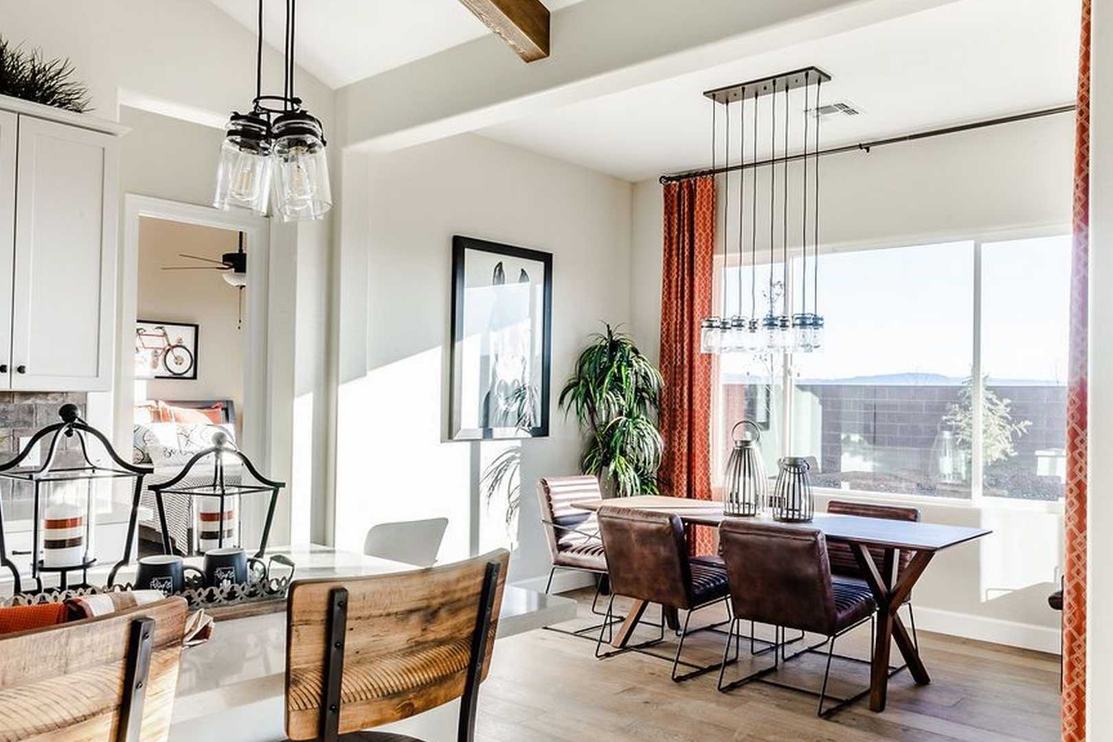 Spacious dining area in The Monarch home with wooden table, leather chairs, pendant lights, and large sunny windows