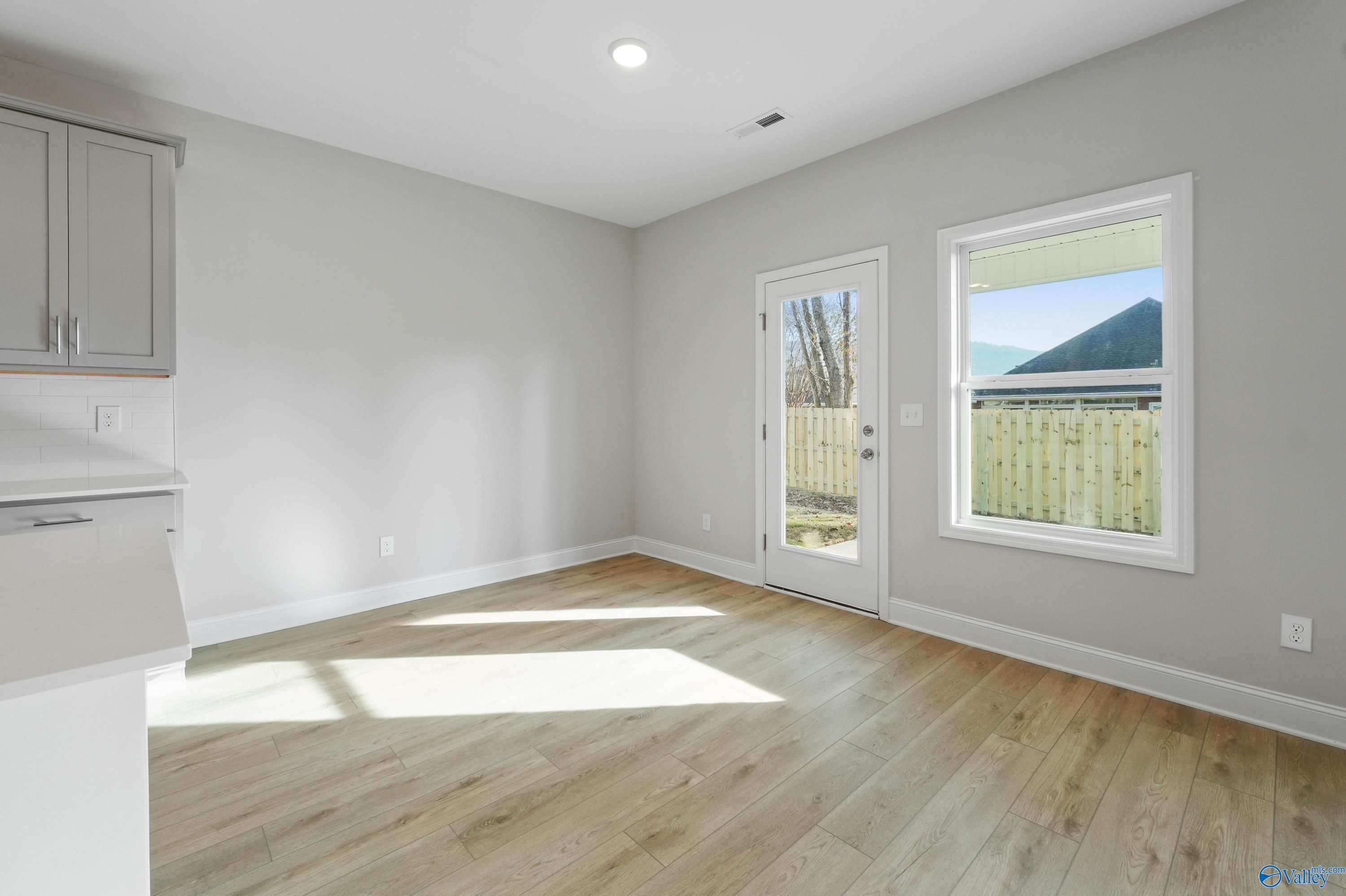 Bright kitchen with white cabinets, hardwood floors, and sliding doors to fenced backyard in Davidson Homes The Camden B, Huntsville AL
