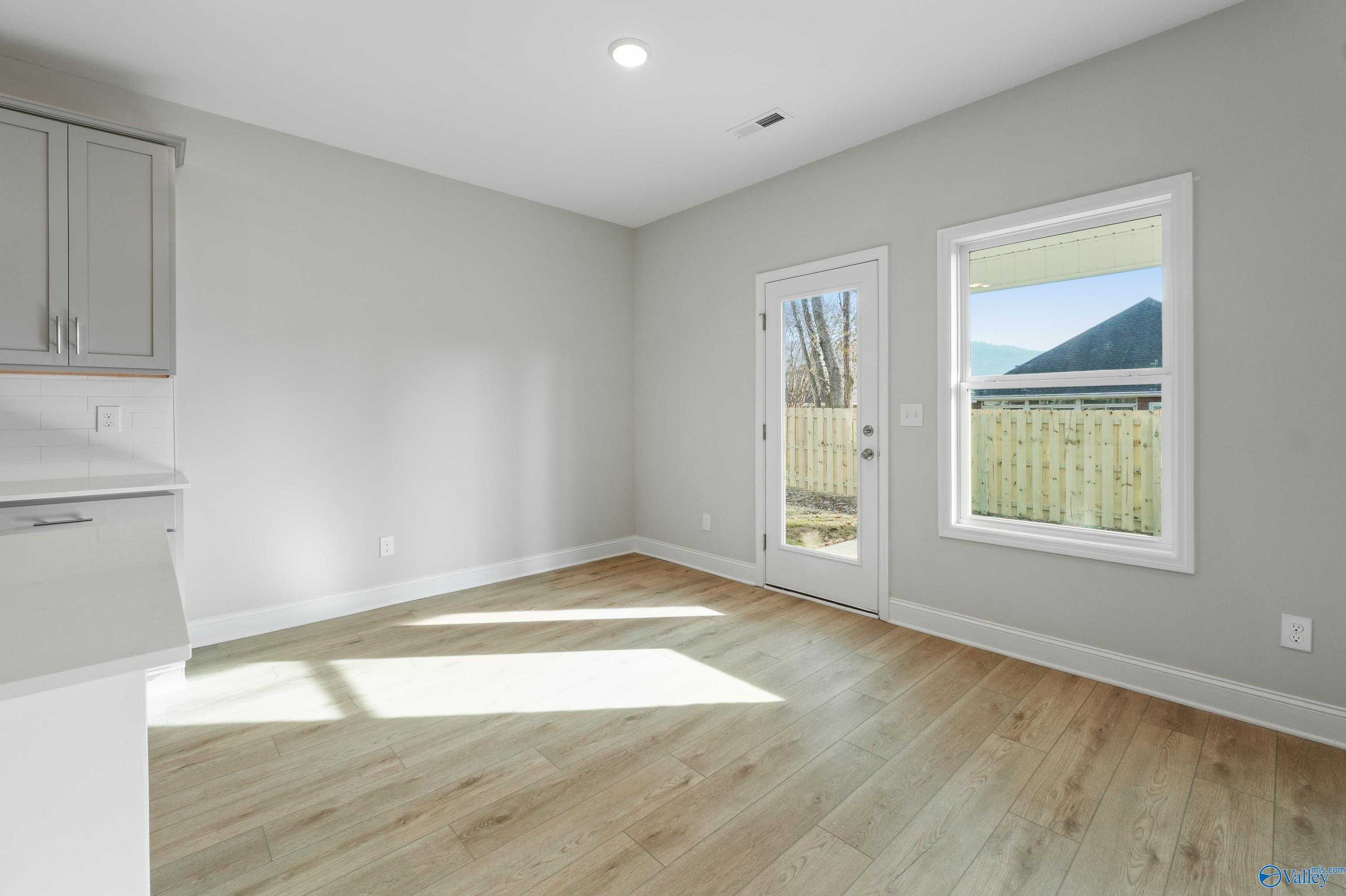 Bright kitchen with white cabinets, hardwood floors, and sliding doors to fenced backyard in Davidson Homes The Camden B, Huntsville AL