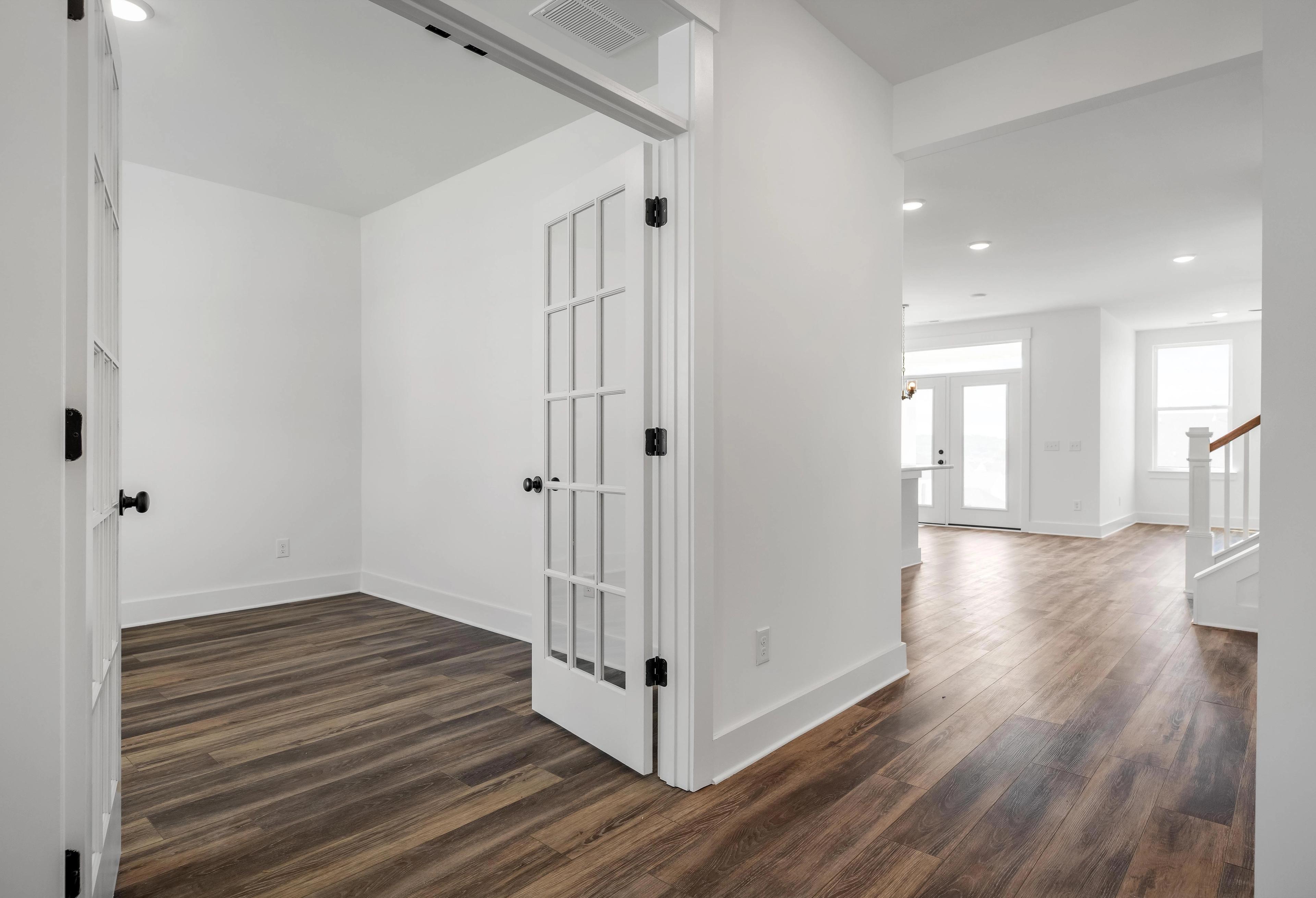Bright home office with French doors and wood-look flooring inside The Cedar home design by Davidson Homes.