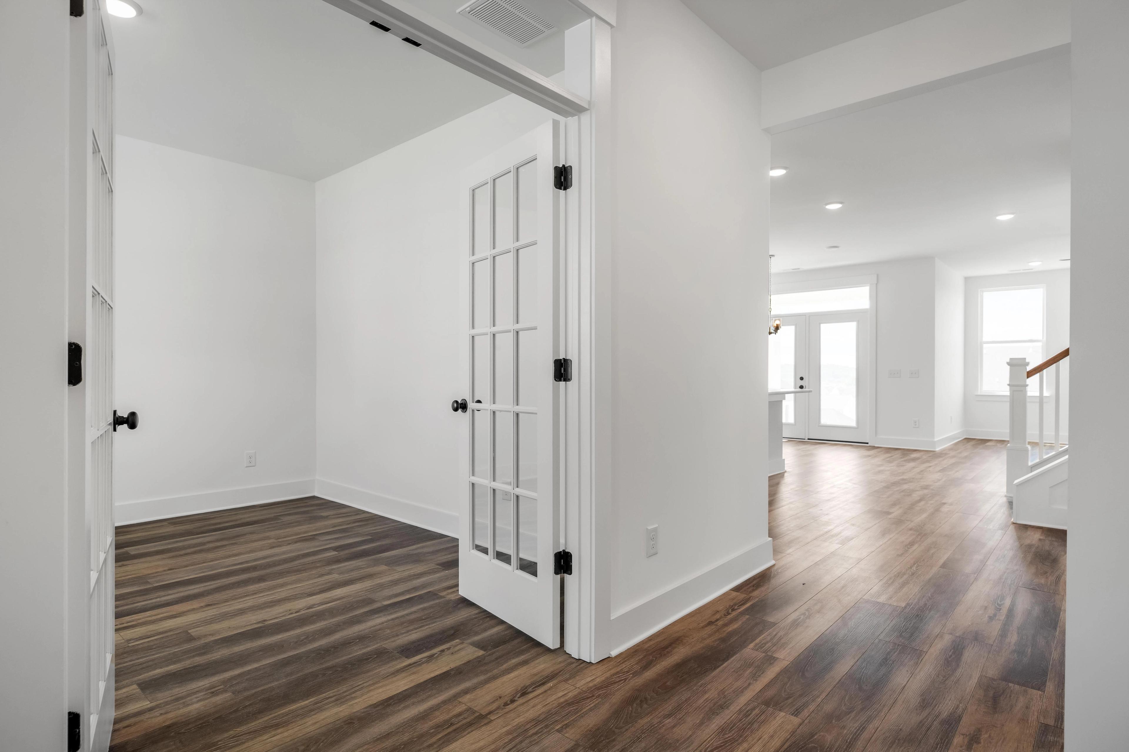 Bright home office with French doors and wood-look flooring inside The Cedar home design by Davidson Homes.