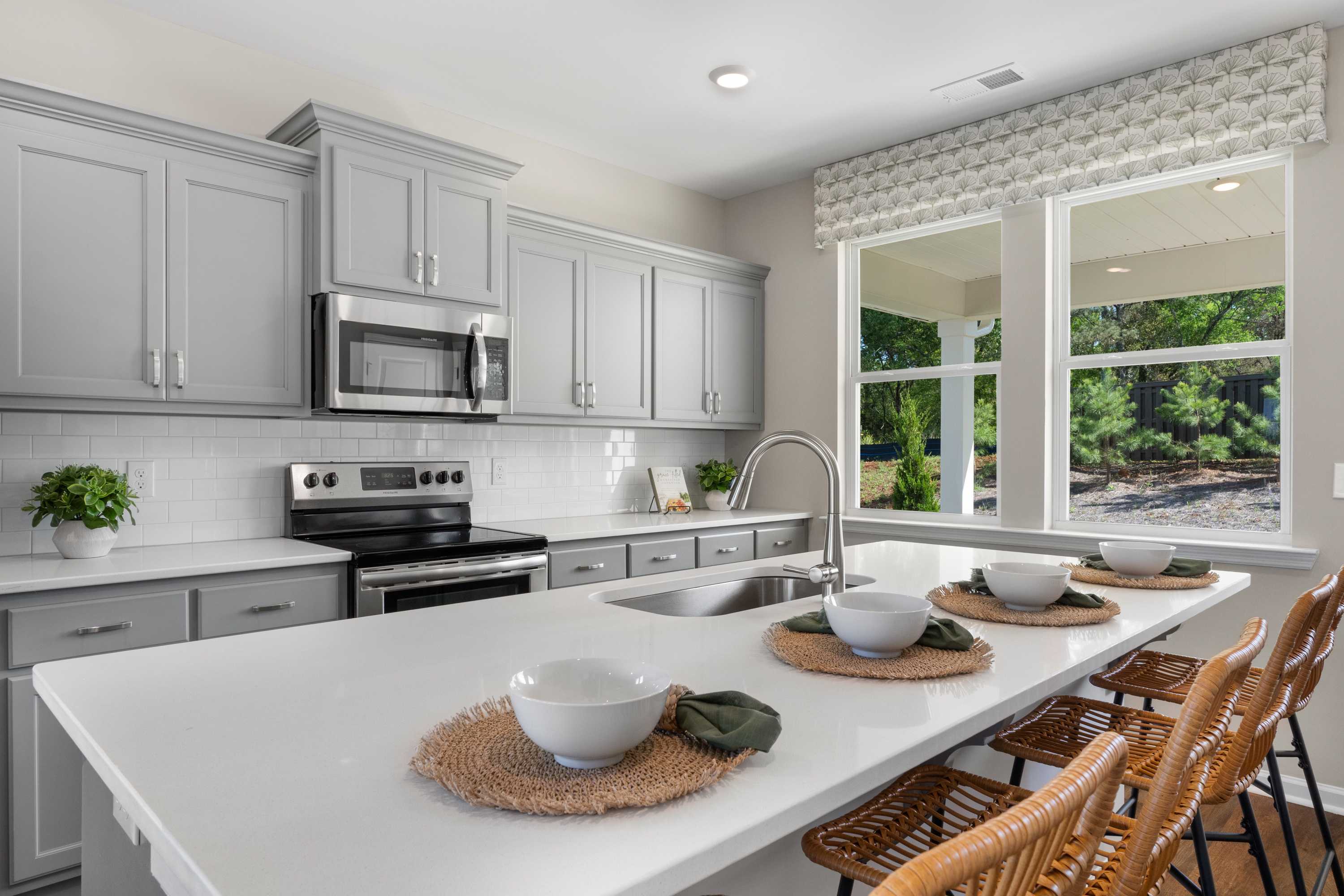 Spacious modern kitchen in Evergreen Mill, Madison AL with gray shaker cabinets, white island, stainless appliances, and window views