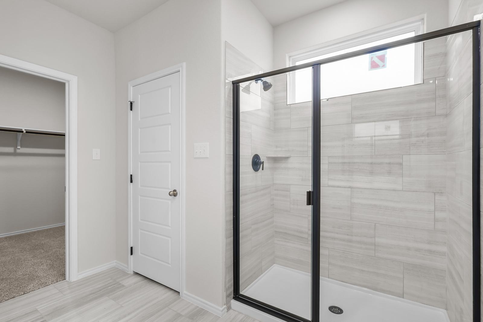 Modern master bathroom shower with tiled walls and glass enclosure in The Sequoia C home design by Davidson Homes.
