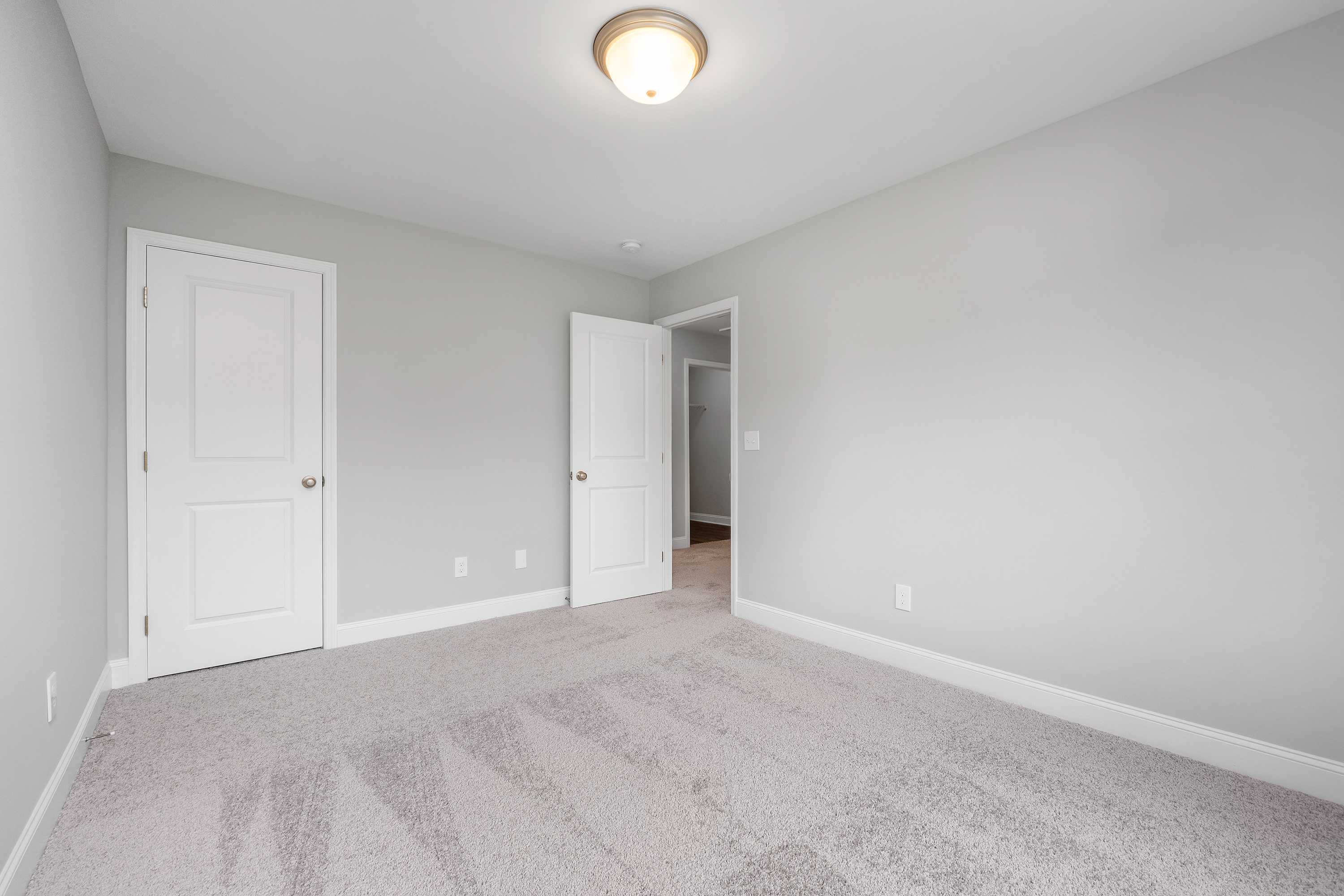Spacious upper-floor master bedroom in The Aiken with light gray walls, white paneled doors, beige carpet