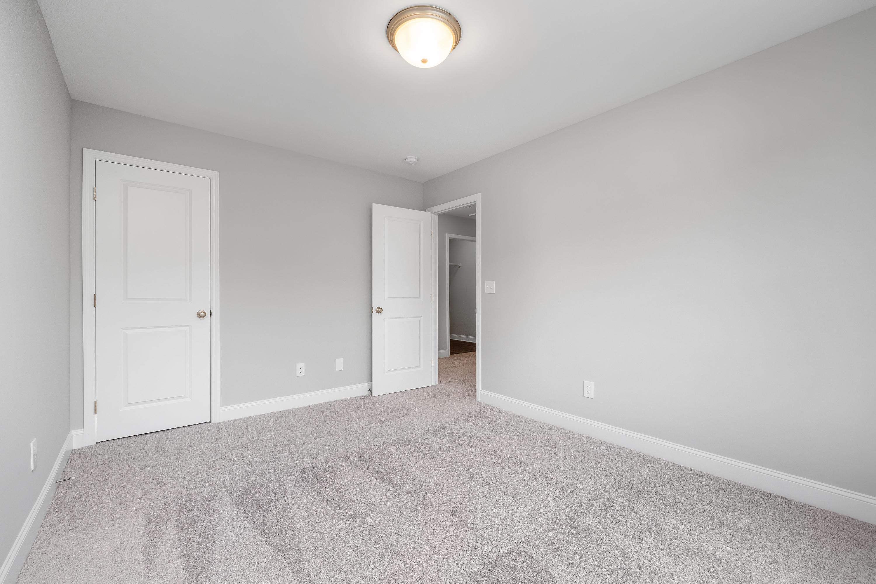 Spacious upper-floor master bedroom in The Aiken with light gray walls, white paneled doors, beige carpet