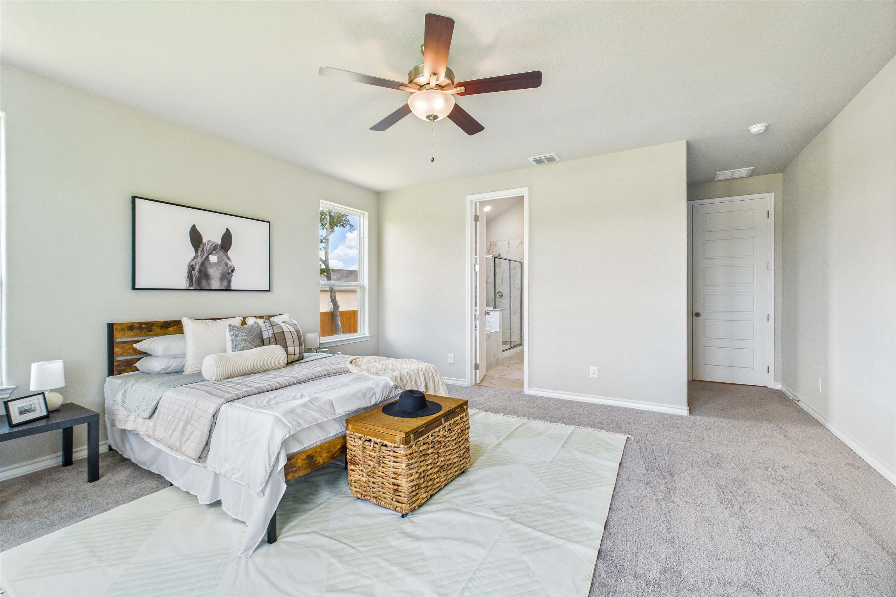 Spacious master bedroom in The Foster featuring a private ensuite bath, ceiling fan, and modern farmhouse decor.