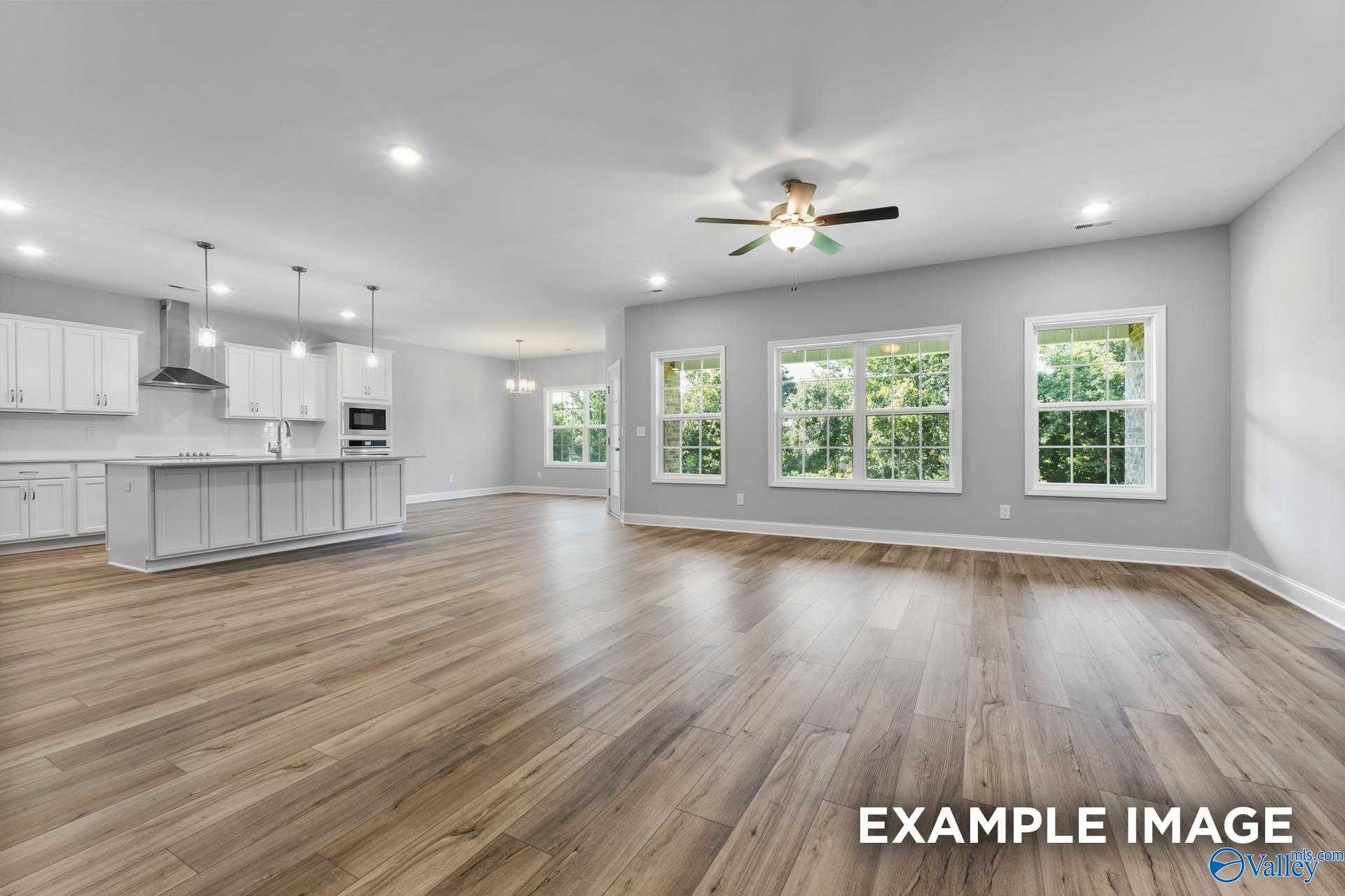 Spacious open-concept great room with kitchen island, hardwood floors, large windows in The Rockford D, Hazel Green, Alabama