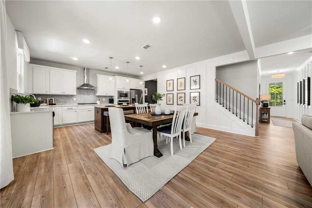 Open-concept kitchen and dining area with white cabinets, island, wooden table in The Hickory B 5-bedroom home, Riverwood, Dallas, Georgia
