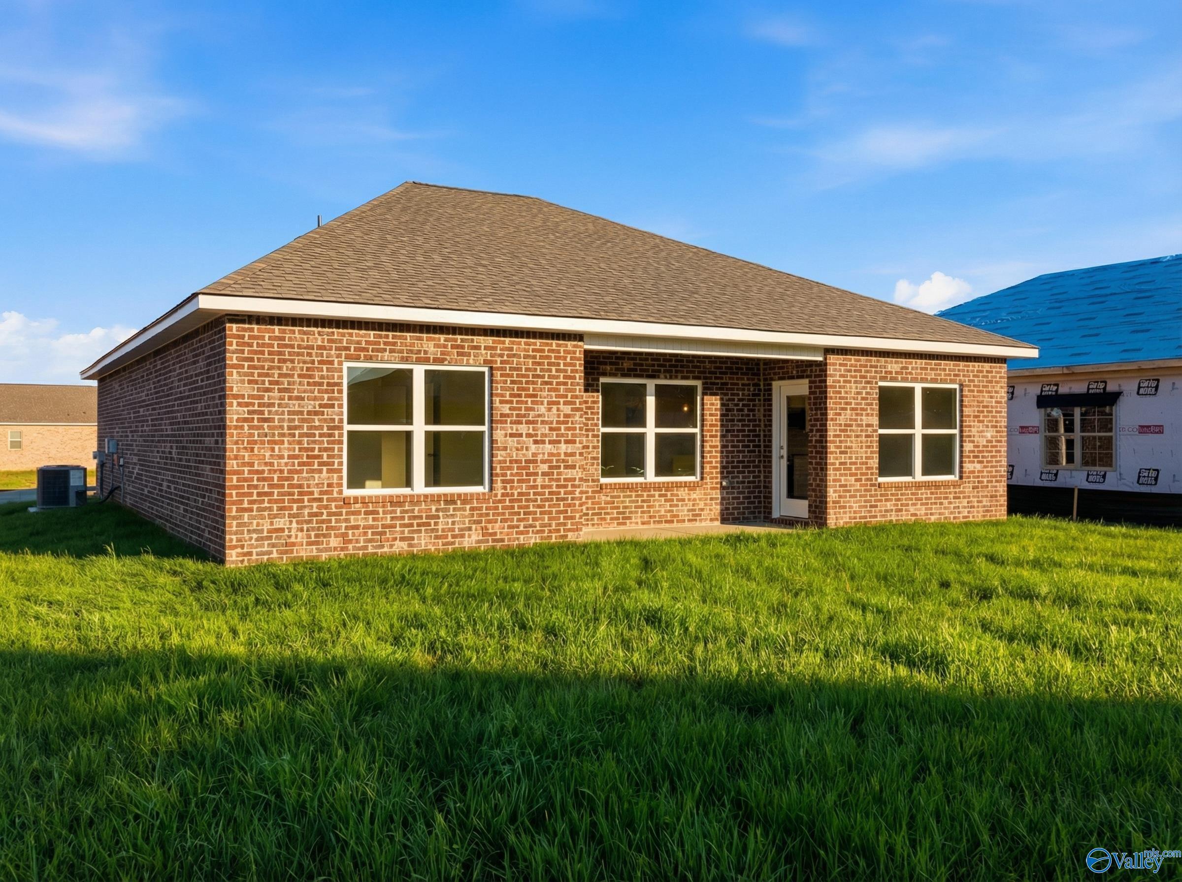 Red brick single-story home with gable roof, large windows, and green lawn in Lynn Meadows, Meridianville, Alabama - Davidson Homes The Asheville C
