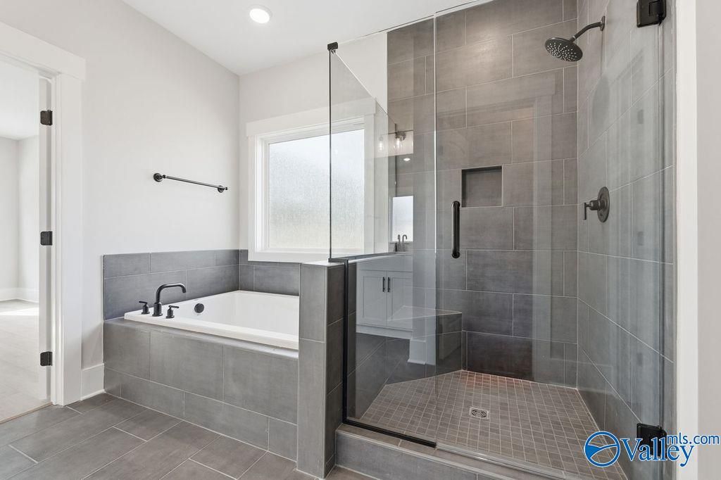 Modern master bathroom featuring freestanding soaking tub and glass-enclosed walk-in shower in Davidson Homes The Rockford, Hartselle, Alabama