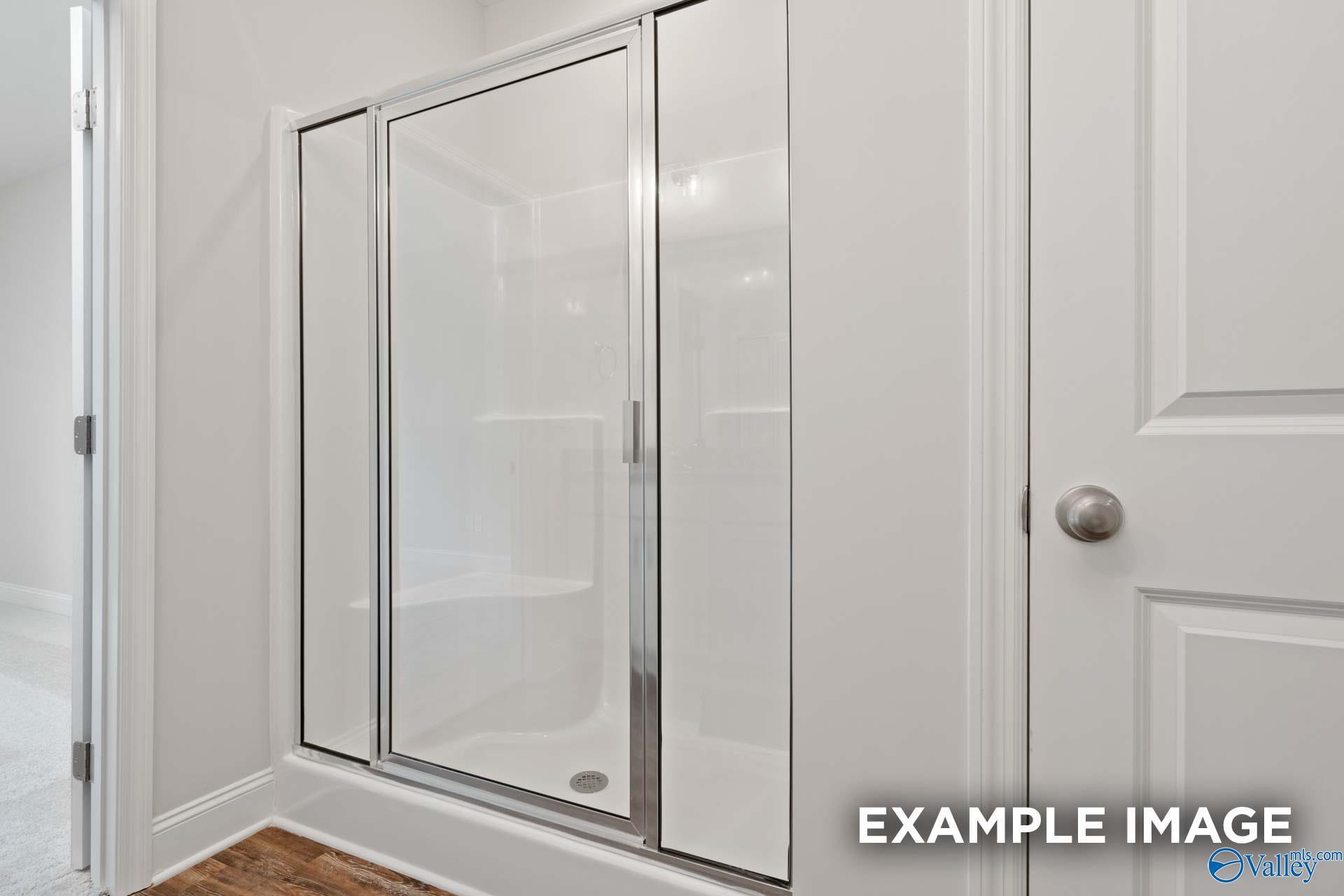 Modern frameless glass shower with white tile surround in master bath of Davidson Homes The Asheville C, Meridianville, Alabama