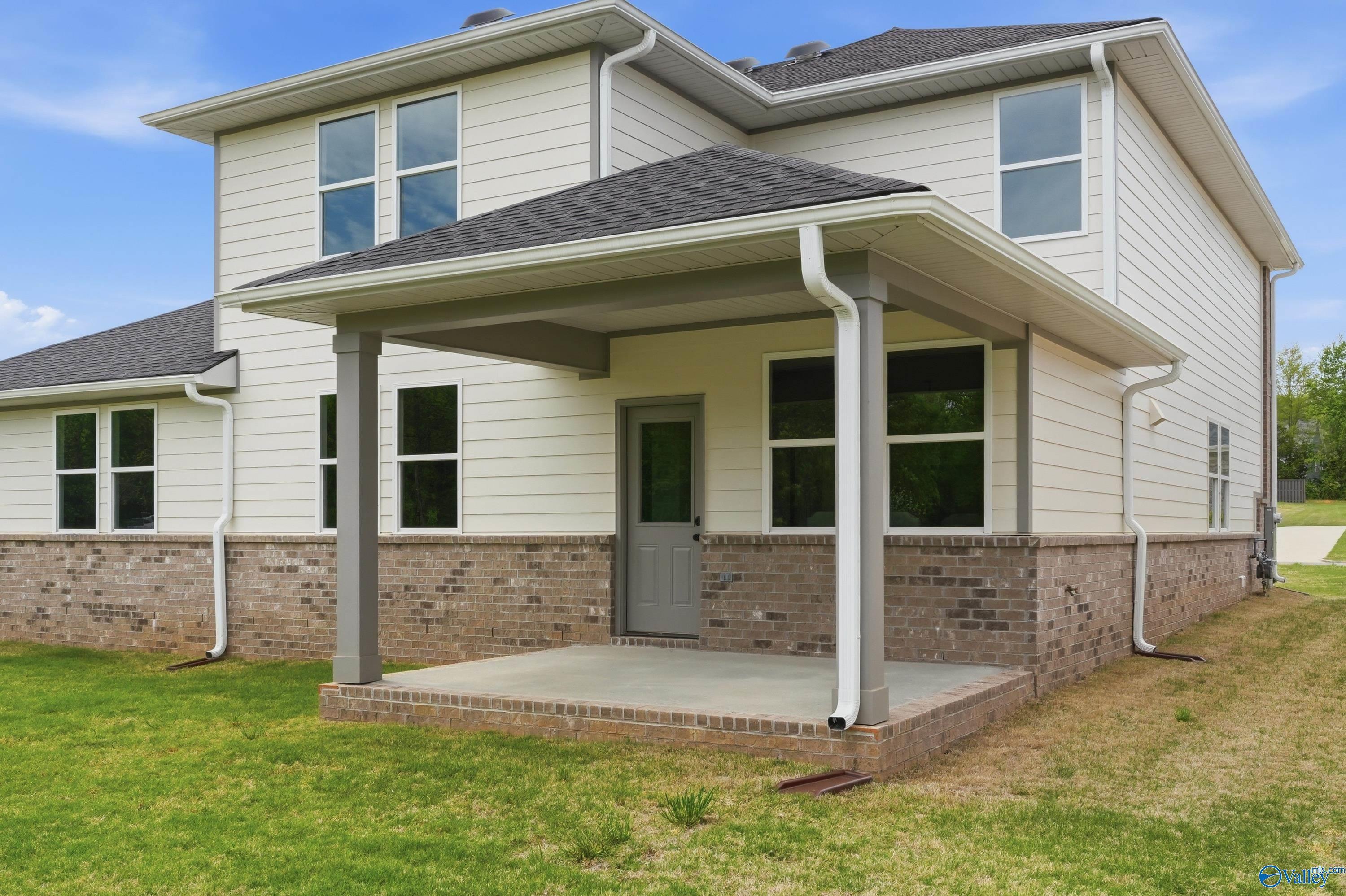Two-story Dorado home exterior with covered front porch, white siding, brick foundation, and green lawn in Riverton Preserve, Huntsville, Alabama