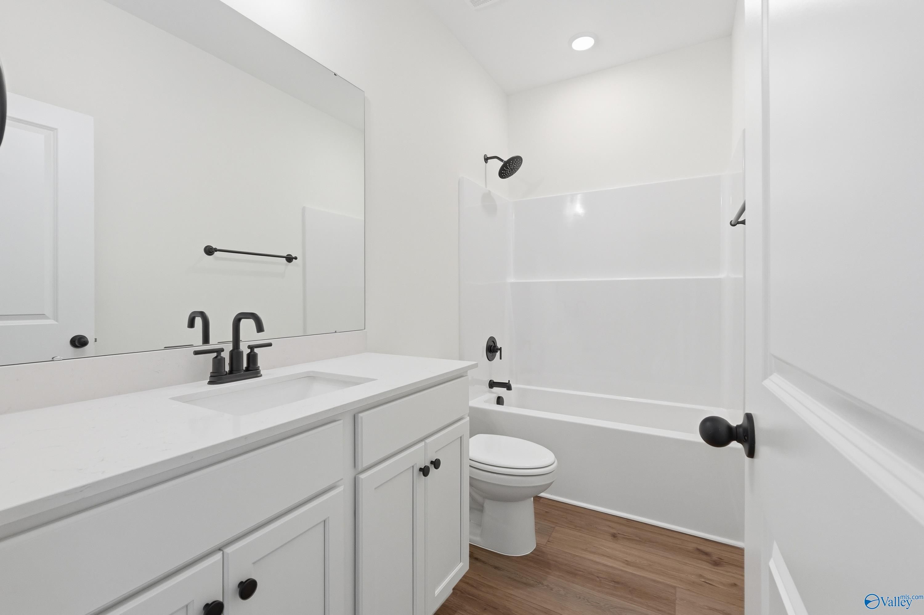 Bright white secondary bathroom with soaking tub, walk-in shower, and single vanity in Davidson Homes The Asheville C, Arab, Alabama