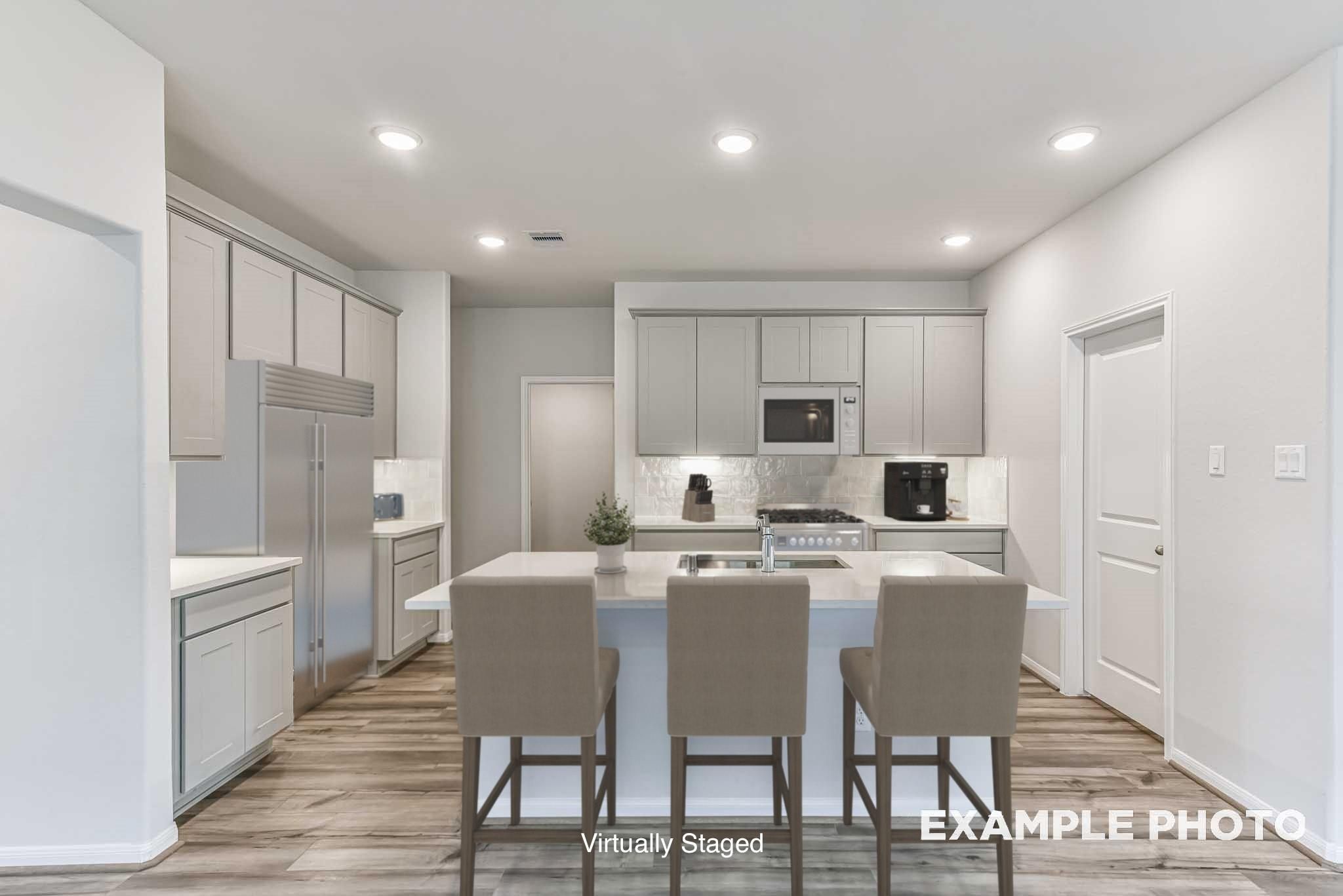 Modern kitchen with light gray cabinets and kitchen island in The Laguna C floor plan at Sunterra, Katy, Texas.