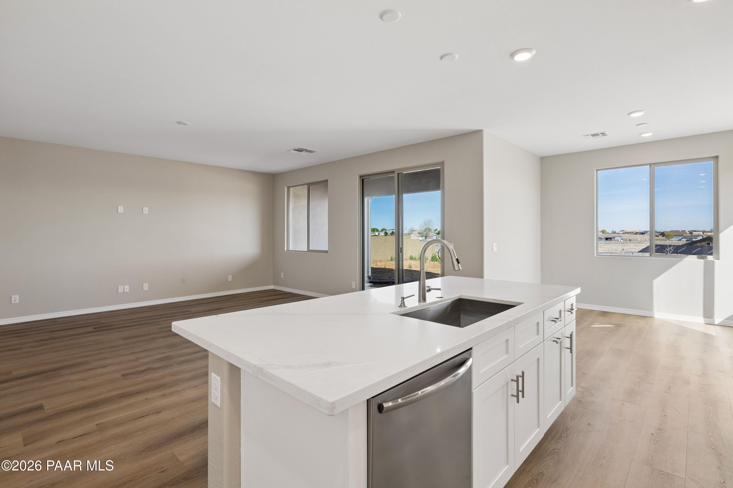 Modern open-concept kitchen with white quartz island, sink, and stainless dishwasher in The Harmony A floor plan, Prescott Valley, AZ