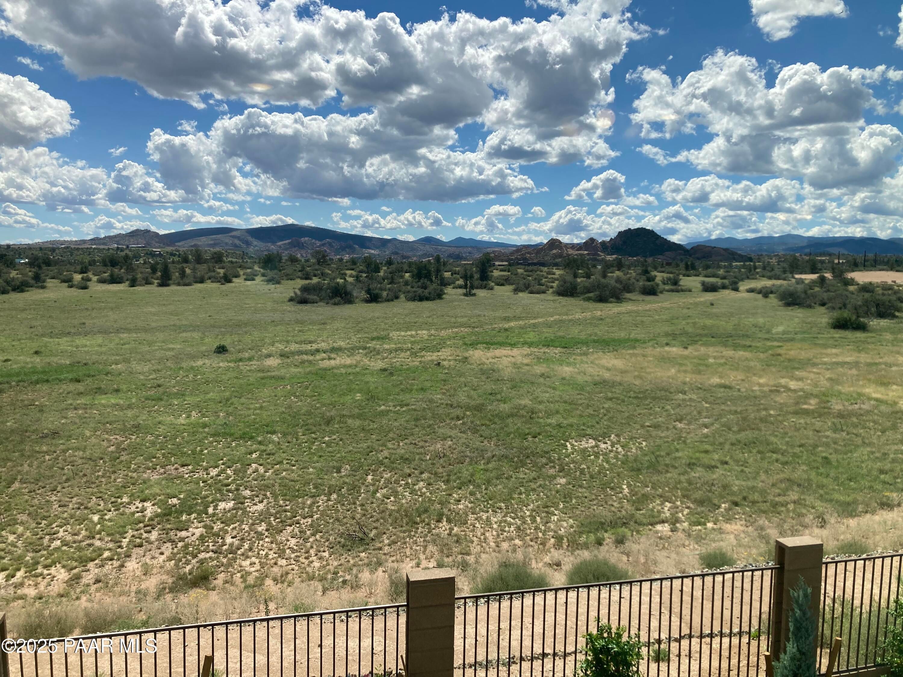 Scenic green valley with distant Prescott mountains under blue skies, viewed from South Ranch 2-bedroom home backyard